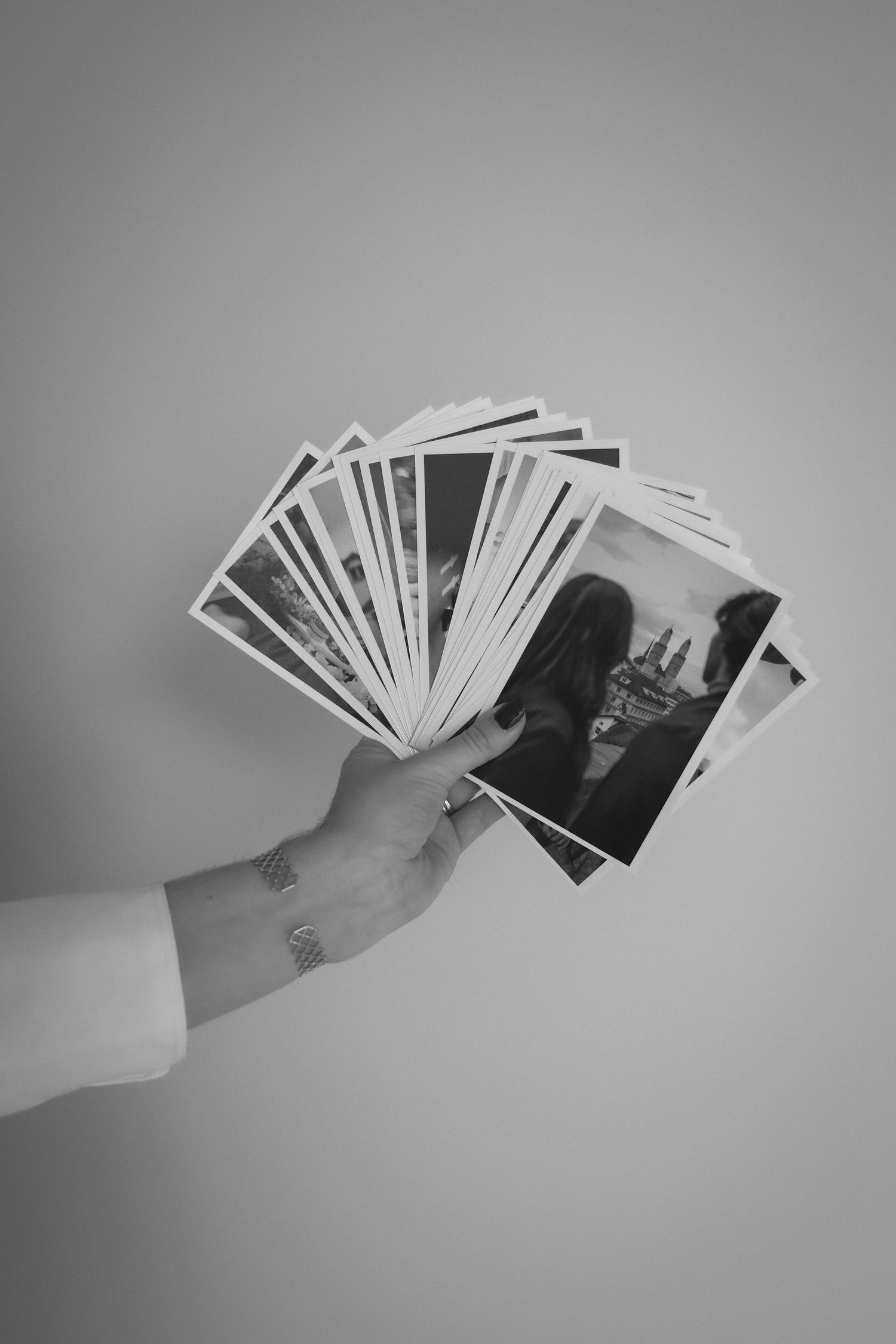 Eine Serie von Schwarz-Weiss-Fotografien, die in einer Hand vor einem hellgrauen Hintergrund aufgefächert werden.