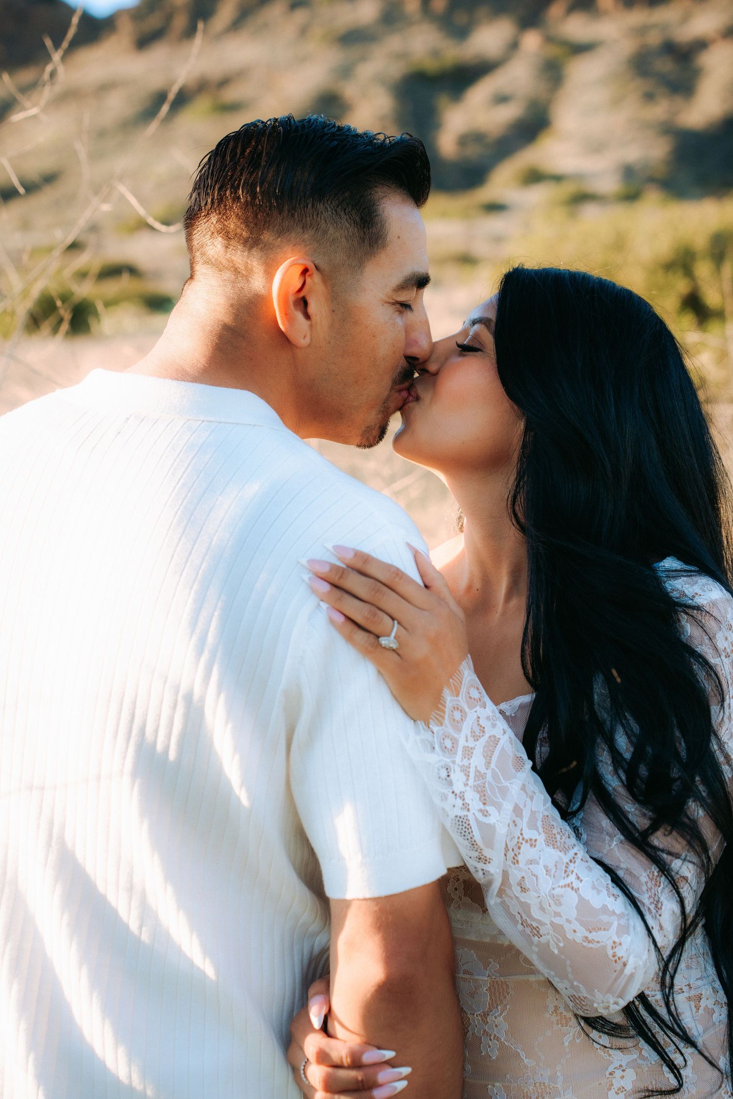 Intimate couple sharing a tender moment against a desert landscape backdrop.