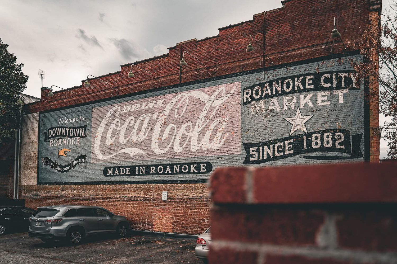 Vintage brick wall with faded Coca-Cola and market signage in Roanoke City.