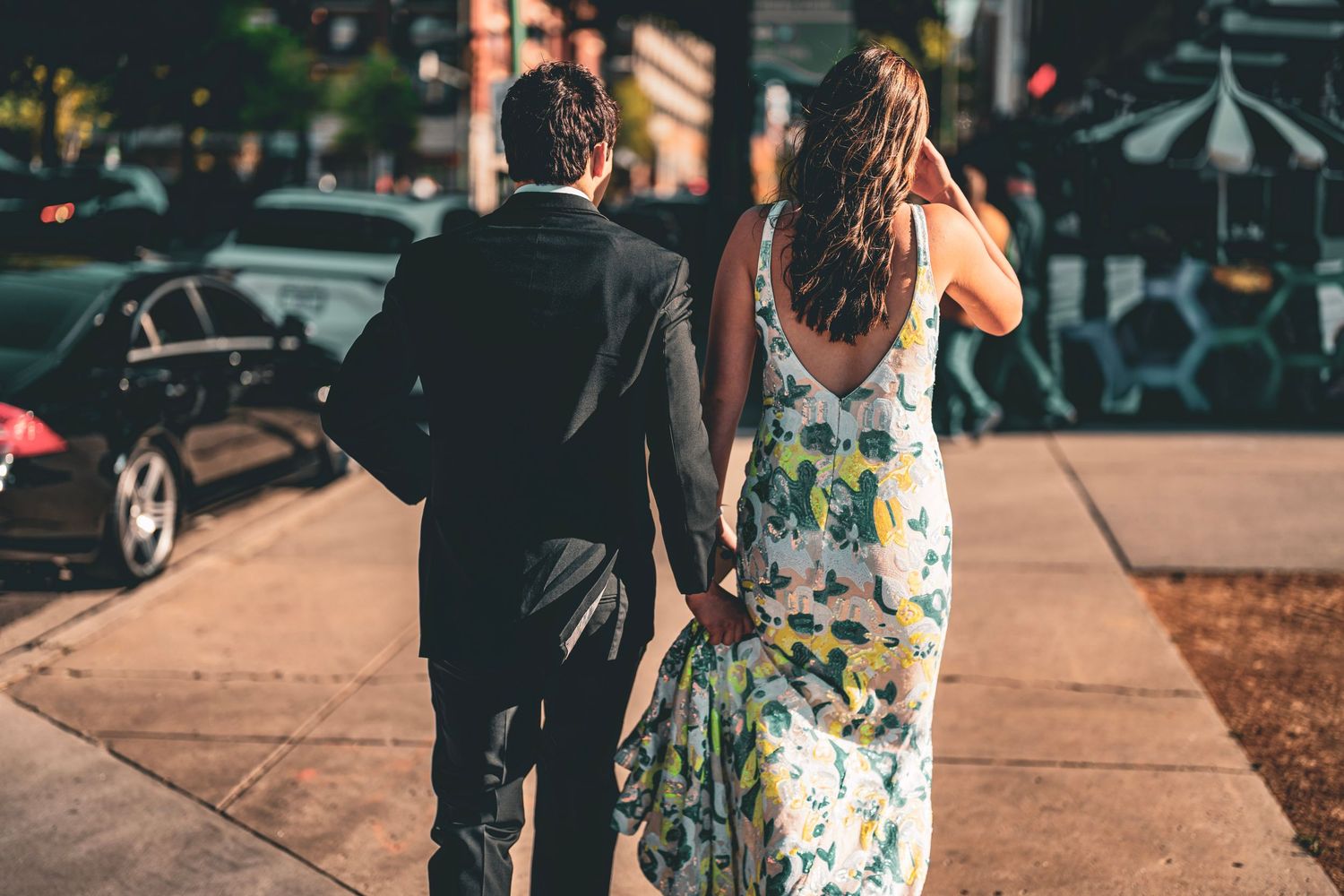 Couple walking together on urban sidewalk in formal attire.