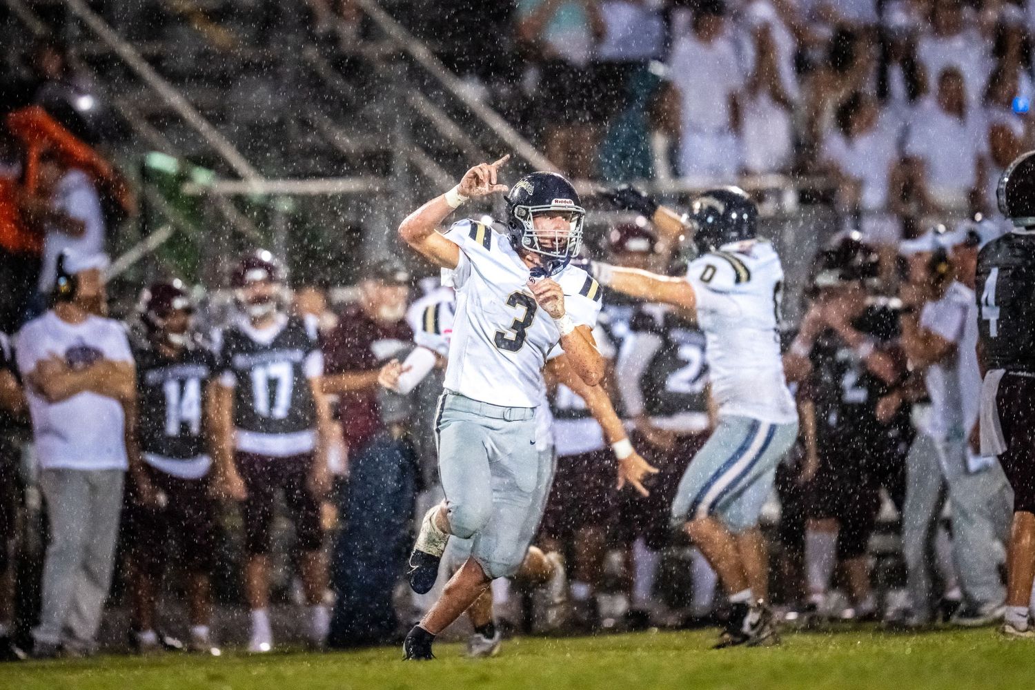 High school football players celebrating a successful field goal kick at a night game.
