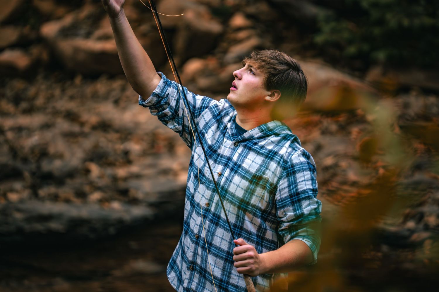 Young boy in plaid shirt enjoying outdoor adventure against natural backdrop.