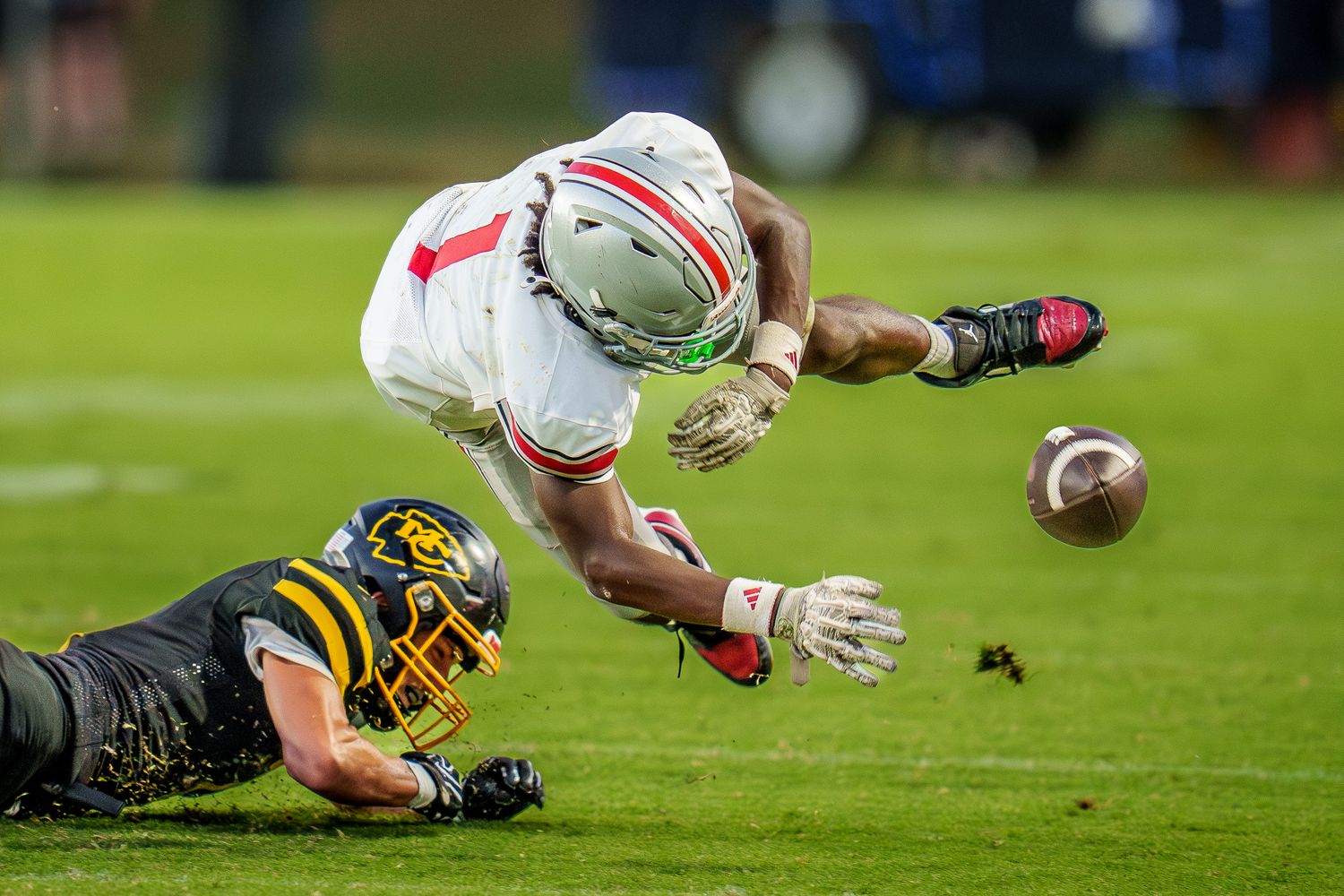 Ohio State football player fumbles the ball during a night game against a Missouri defender on the field.