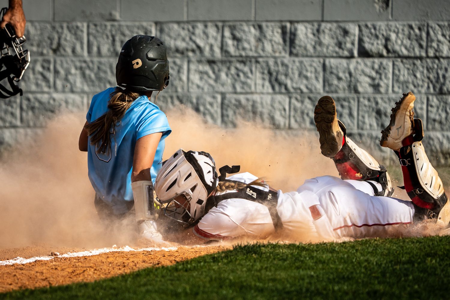 Dramatic sliding play at home plate creating a cloud of dust during baseball game.