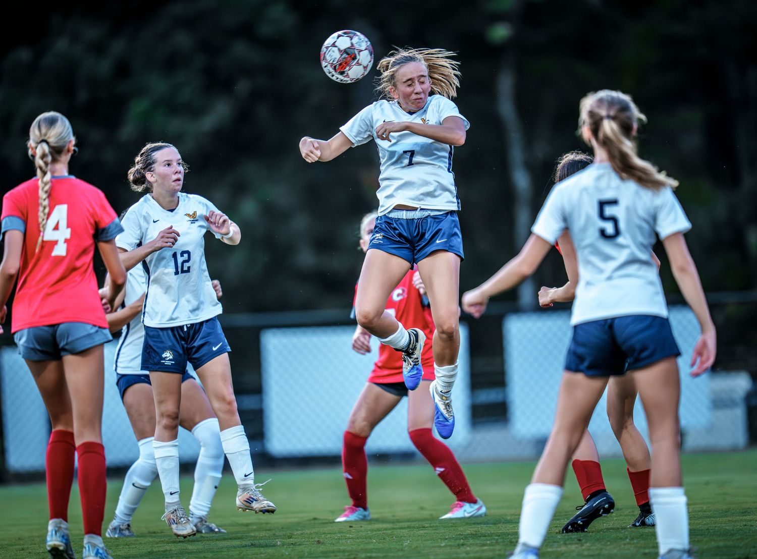 Women's soccer teams battling for possession during a competitive match.