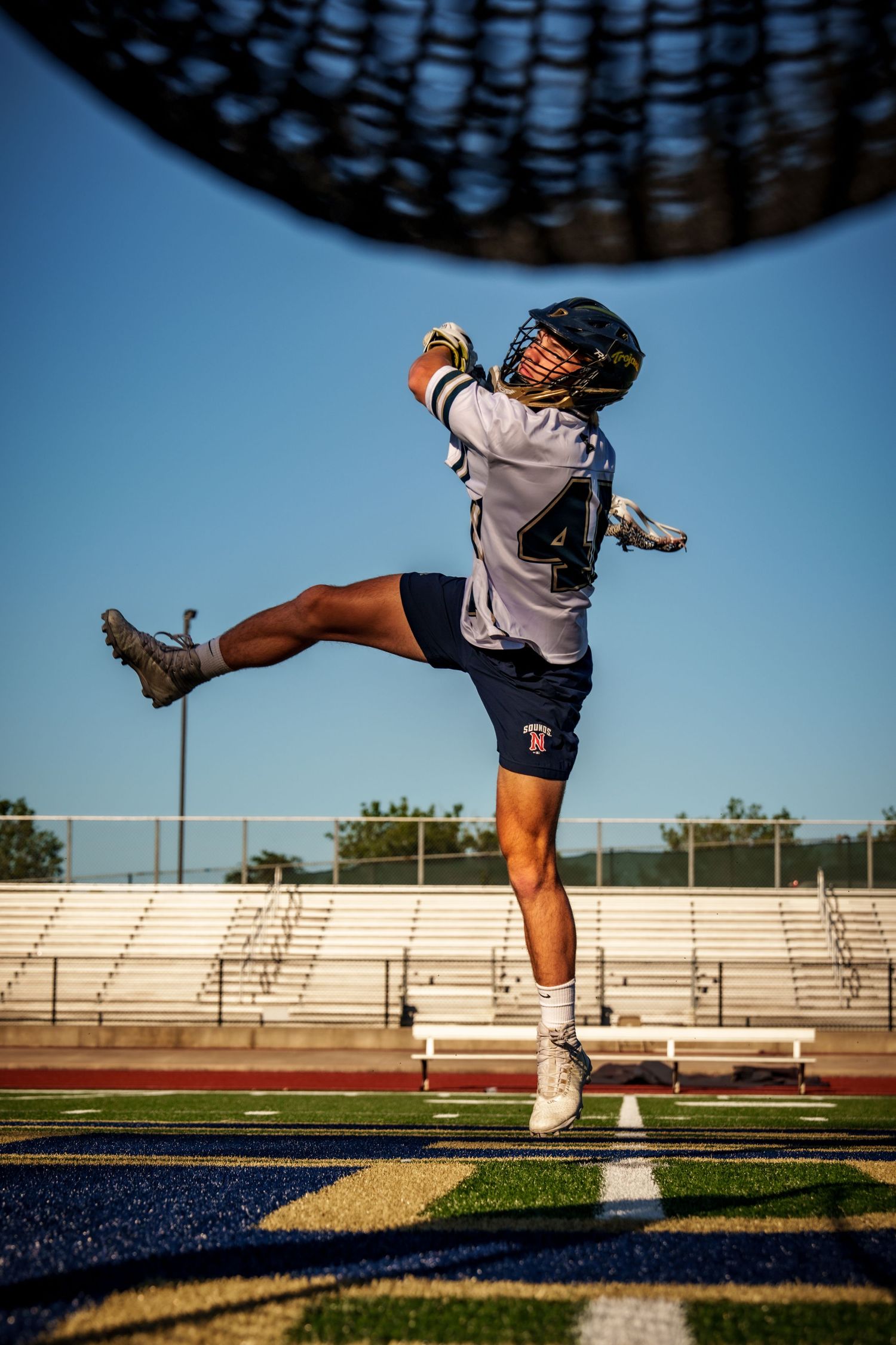 Athlete practicing kicking techniques on sports field under blue sky.