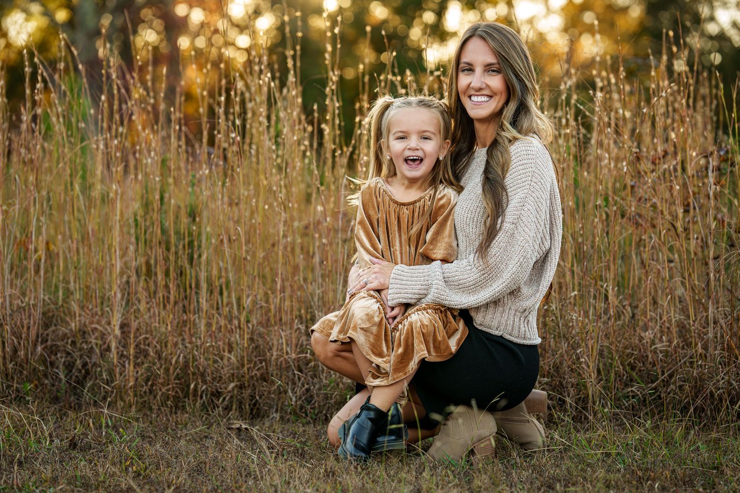 Family enjoying playful moments together in a sunlit meadow during golden hour.