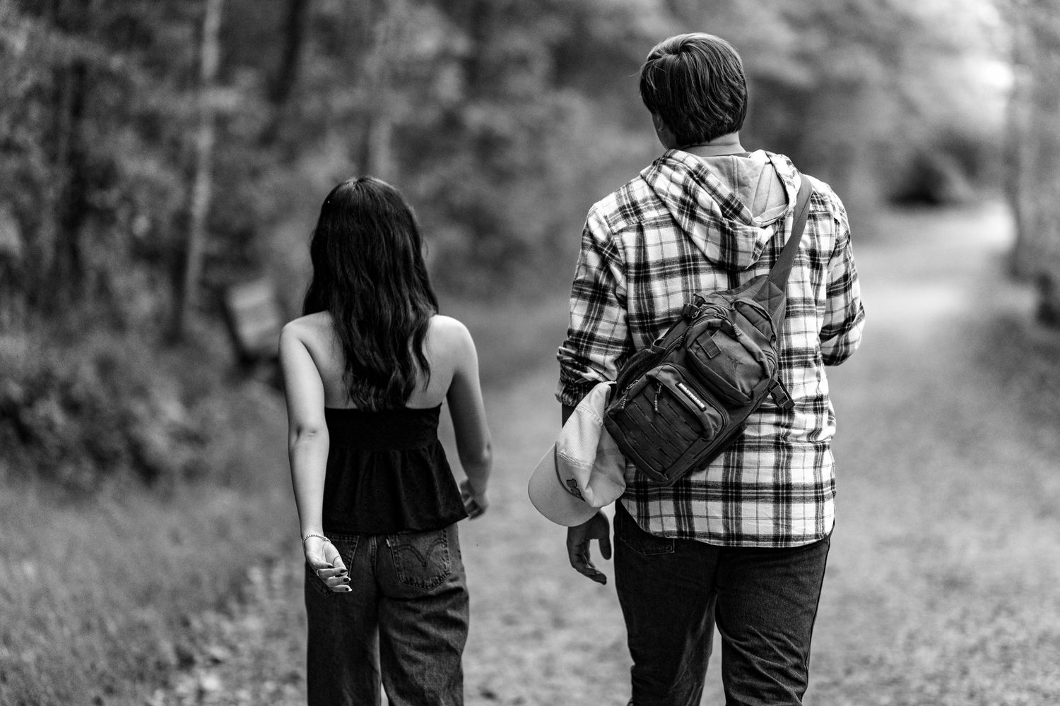 Couple walking together on tree-lined path in black and white photo.