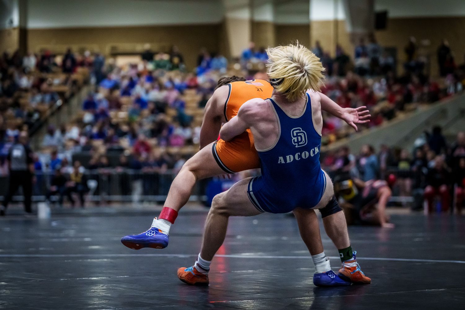 Wrestlers grappling on the mat during an intense match competition.