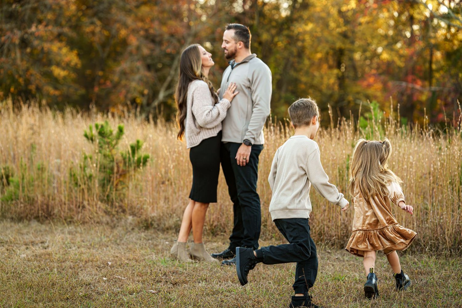 A couple shares a tender moment in a golden autumn field during sunset.