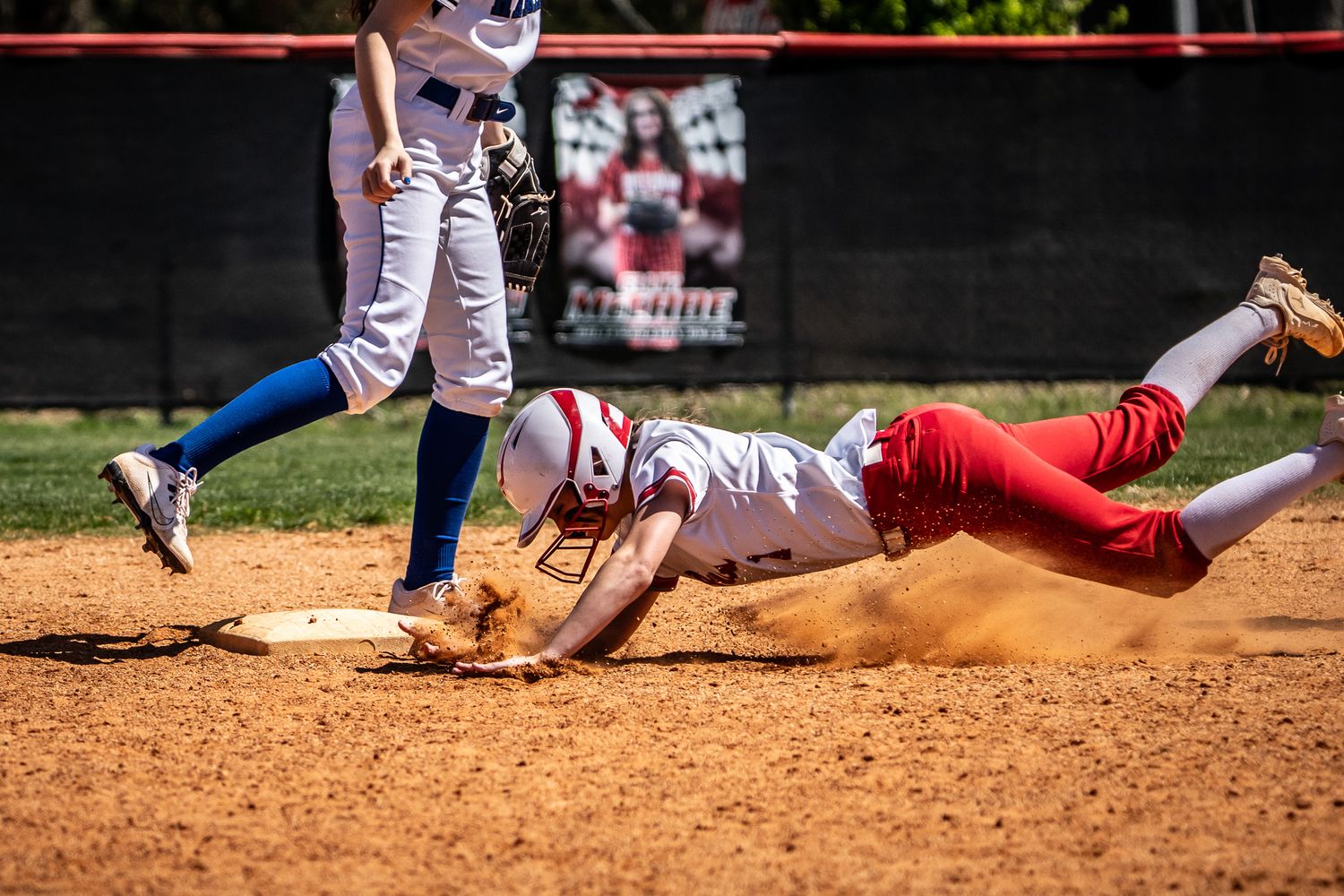 Baseball players sliding into base during an intense play at home plate.