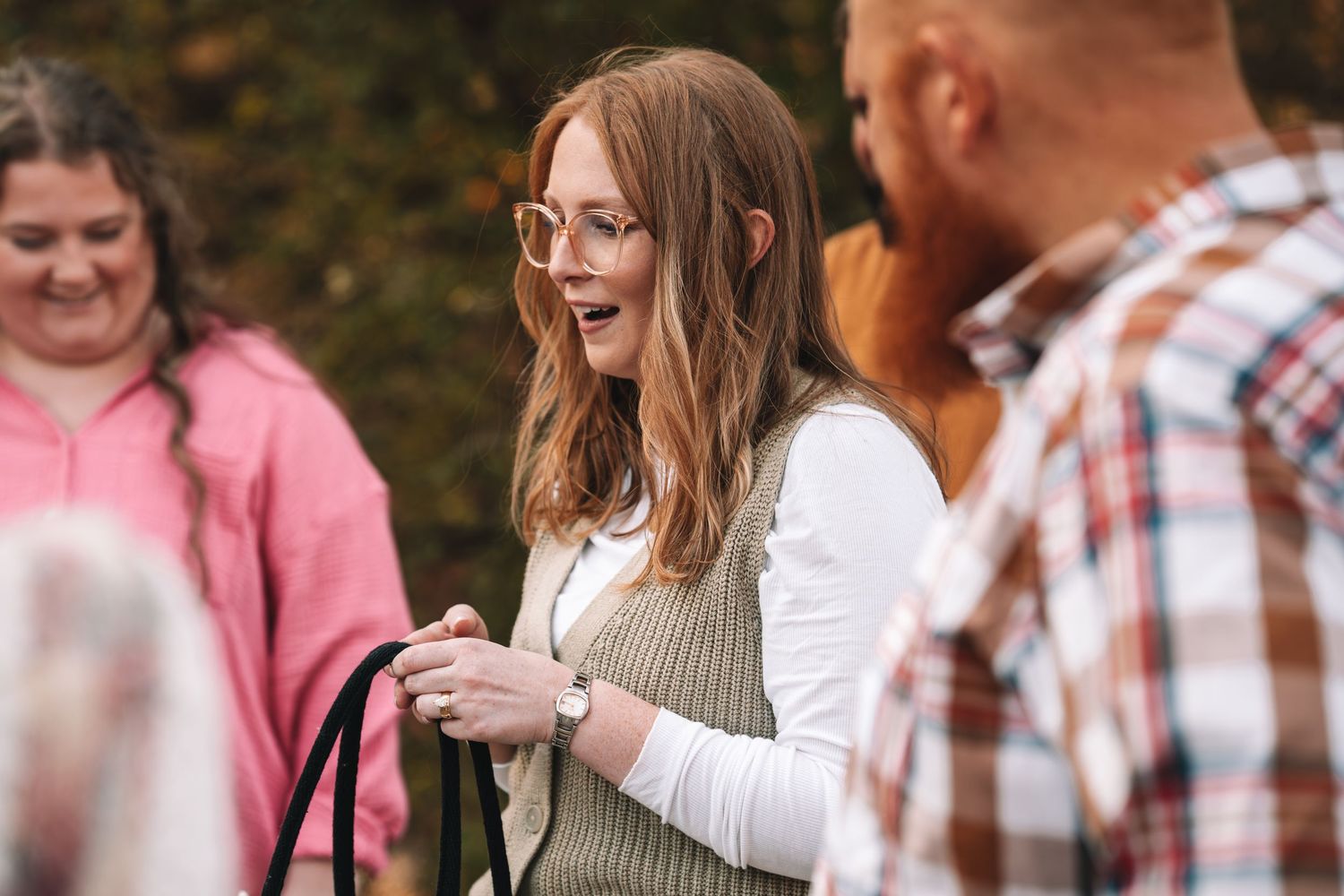 A group of people laughing and enjoying conversation outdoors on a sunny autumn day.