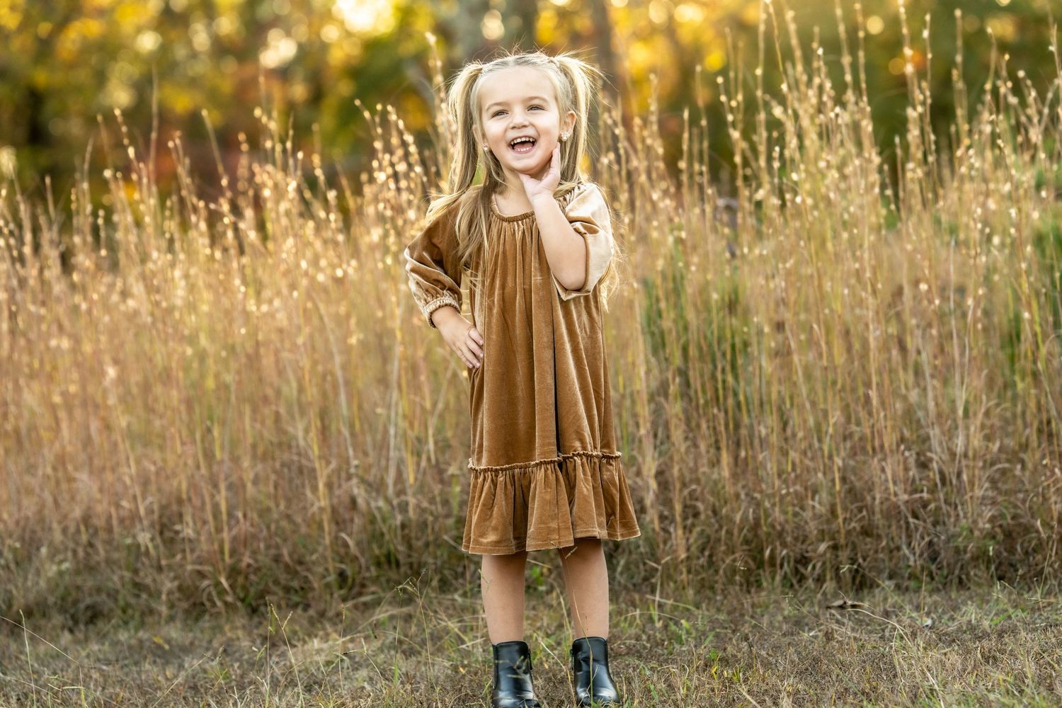 A figure in a brown dress twirls joyfully in a sunlit autumn field with golden tall grass.