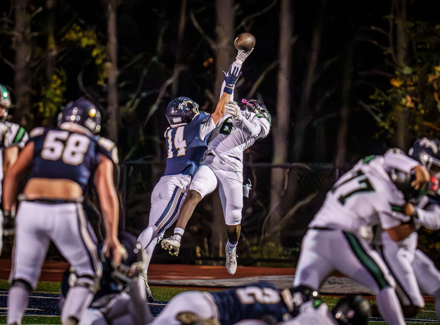 Football players in action during a nighttime game on the field.