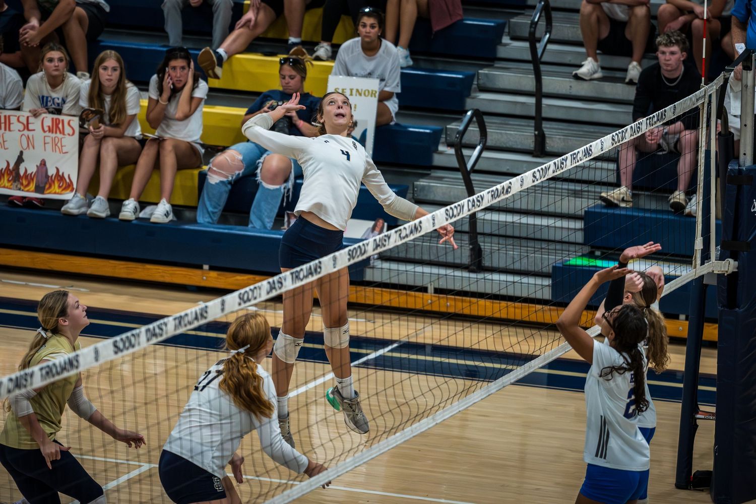 Indoor volleyball match with players positioned near the net during gameplay.