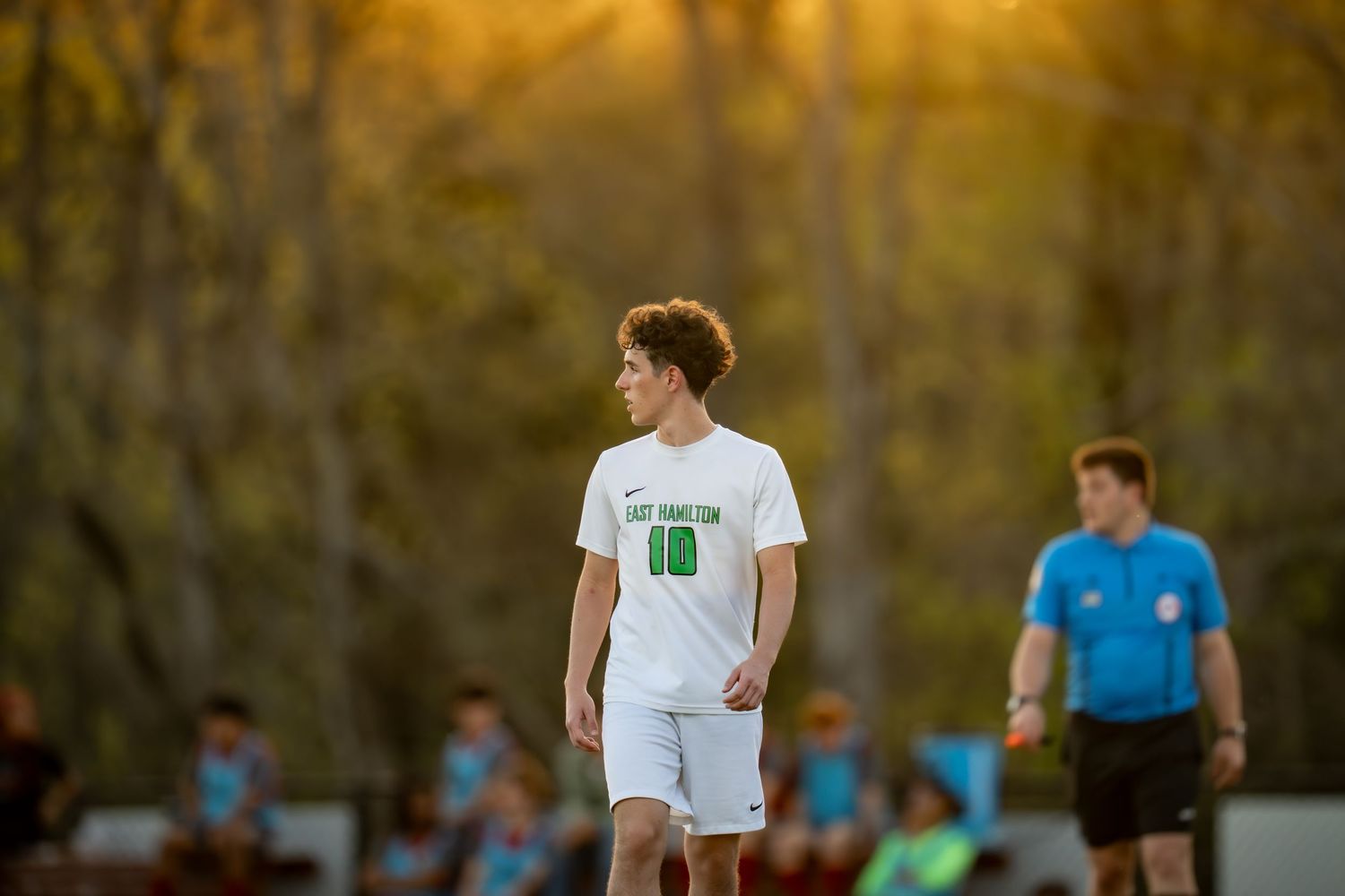 Soccer player wearing number 10 jersey stands on field during golden hour sunset game.