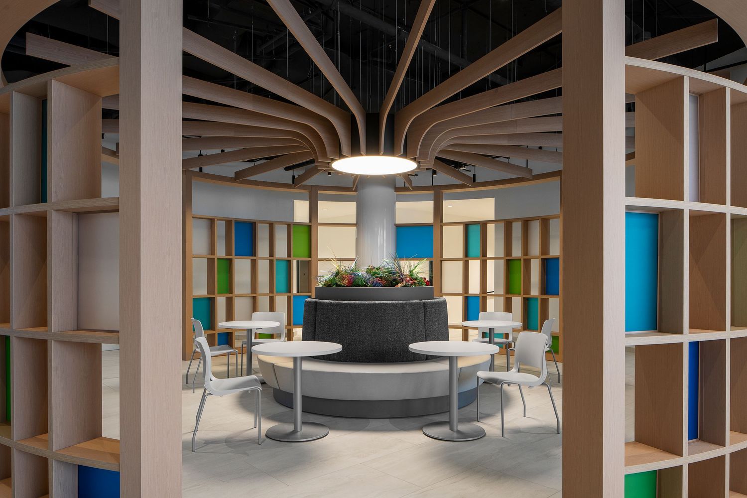Modern office interior with wooden beams, white columns and colorful wall panels in an open workspace design.