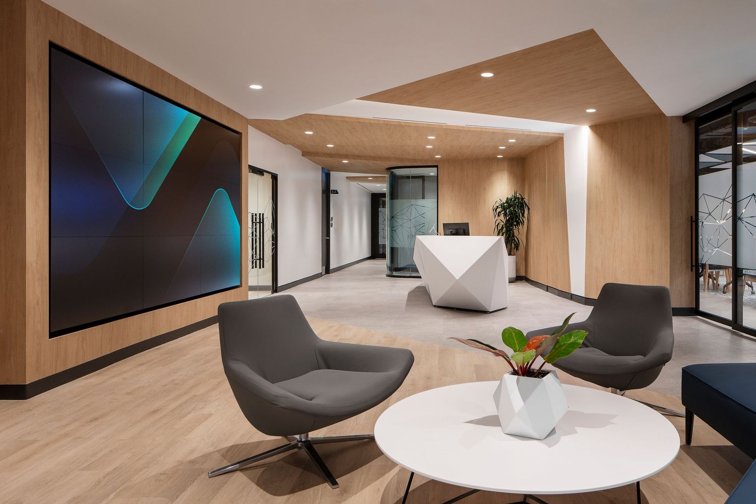 Modern office interior features sleek grey lounge chairs and white marble table with minimalist architectural details.