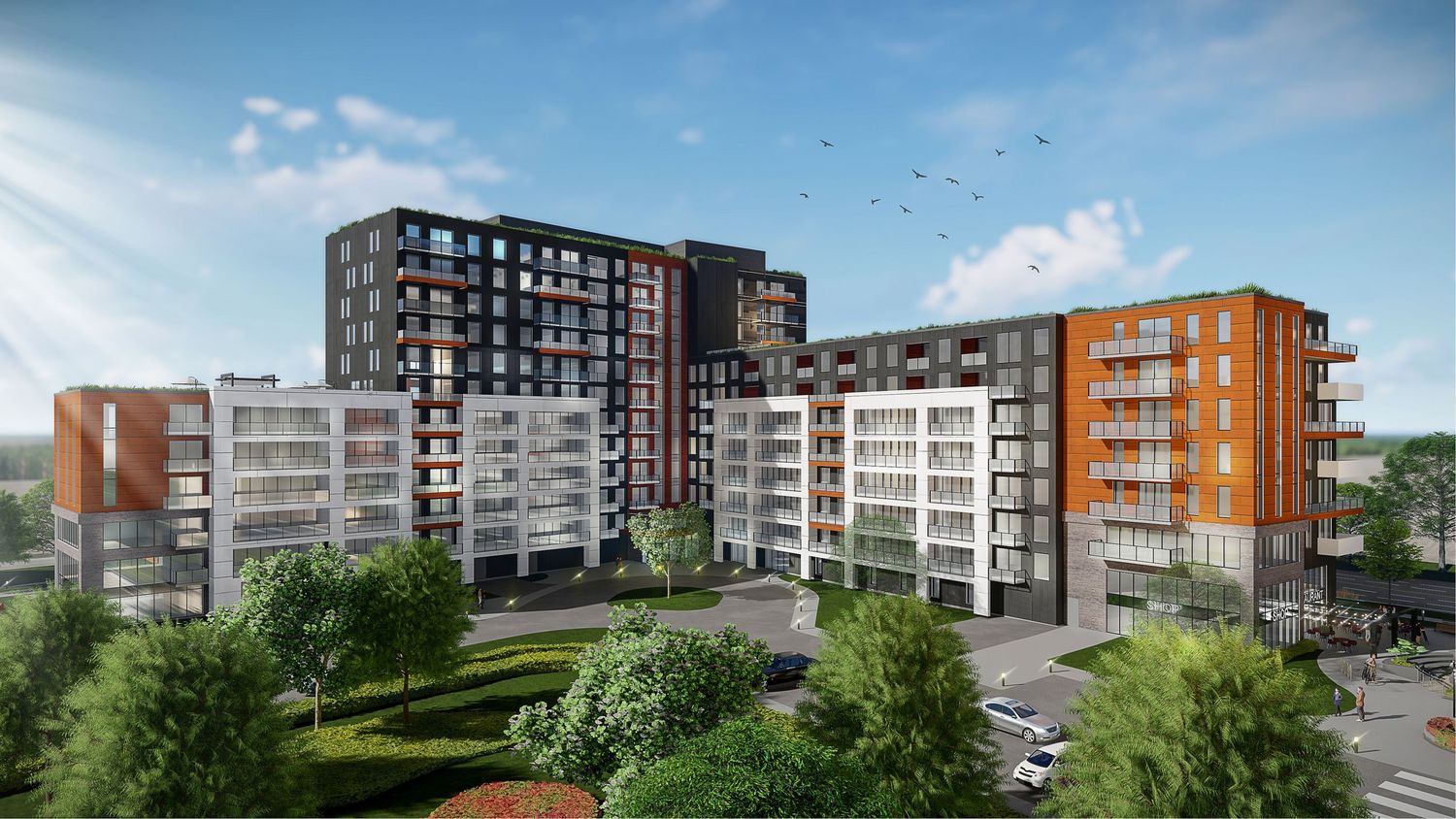 Panoramic view of a modern apartment complex with mixed architectural styles and green landscaping along the perimeter.