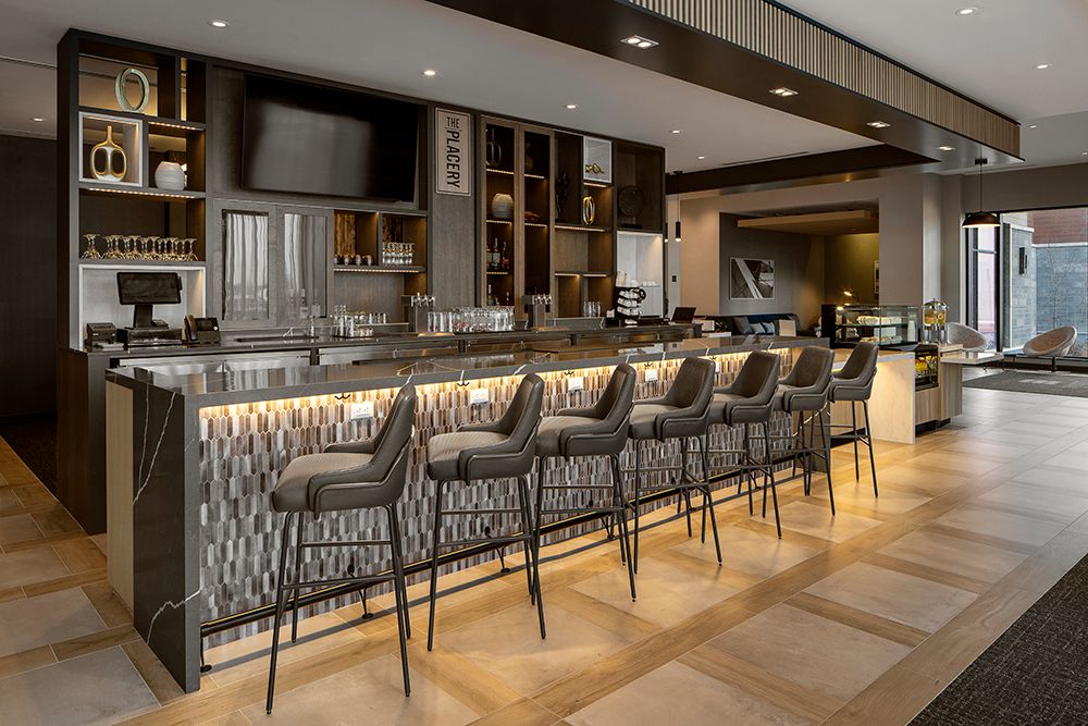 Modern office hallway with sleek gray chairs lined against walls and recessed lighting in the ceiling.