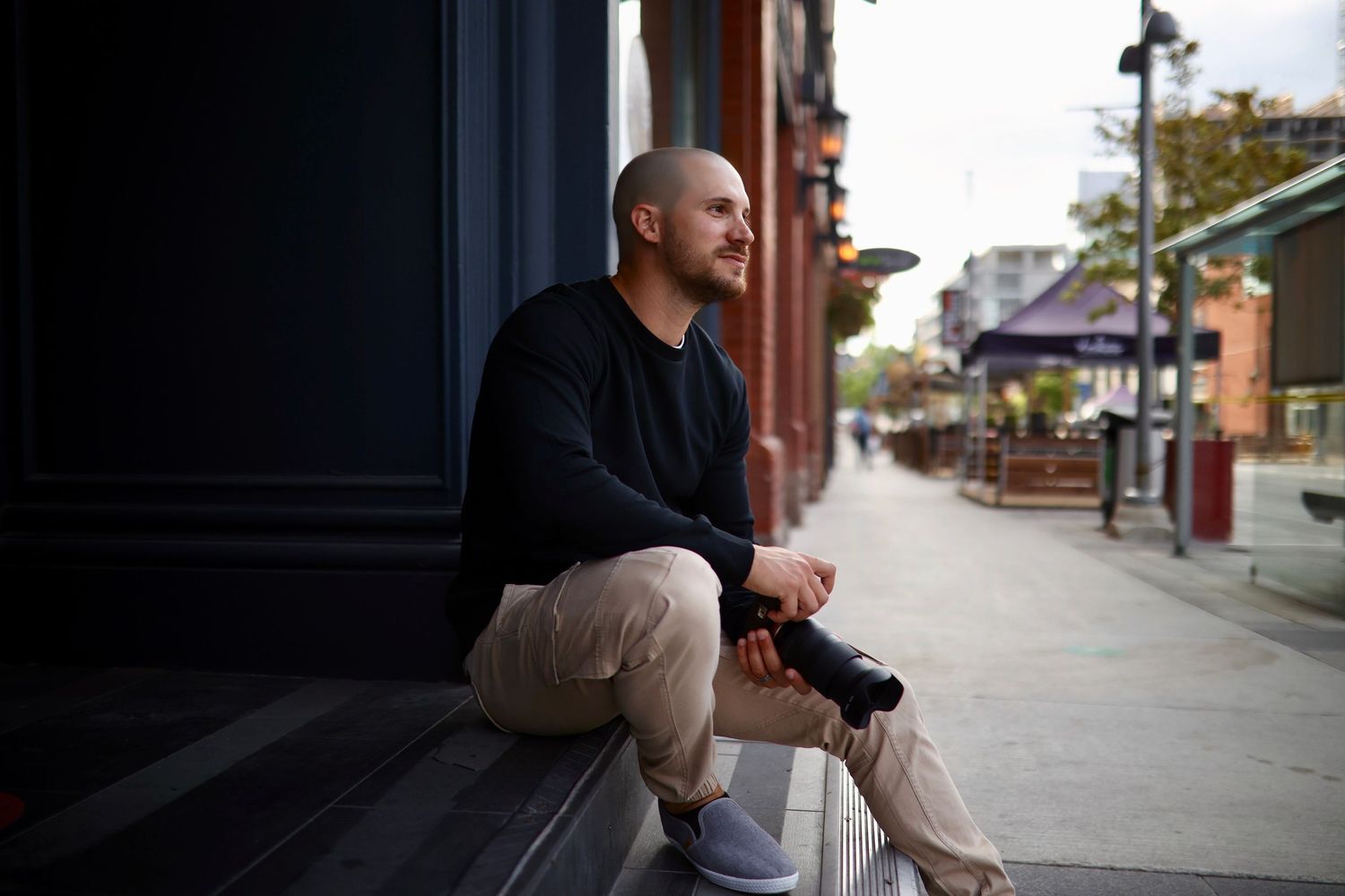 Person sitting on concrete steps with a smartphone in their hand on a city street.