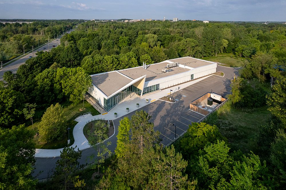 Aerial view of modern buildings and facilities nestled among lush green forest canopy on a sunny day.