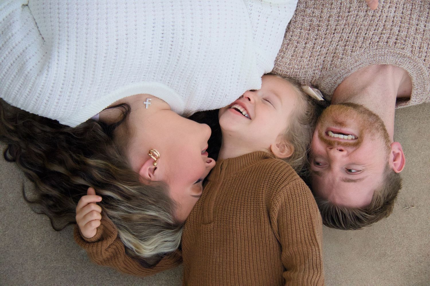Professional lifestyle family photography by Haug & Bees Media featuring a mother, father, and young child laughing together in a natural, o