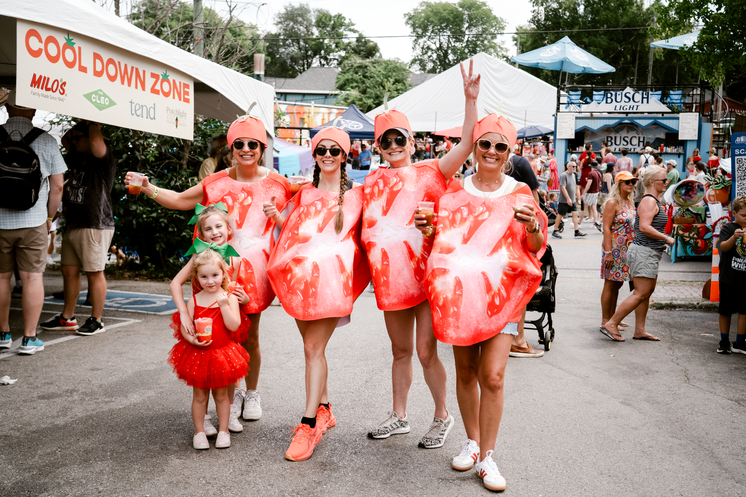 Crowd of people in matching red outfits walking together at a street festival.