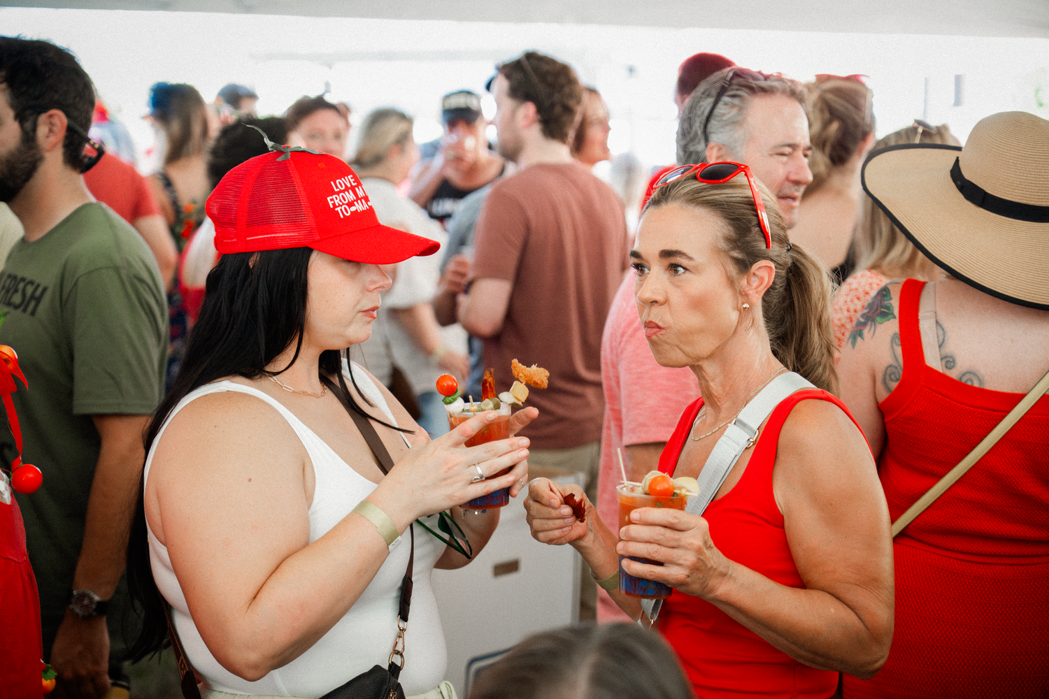 Large group of people in red attire socializing at an outdoor festival.