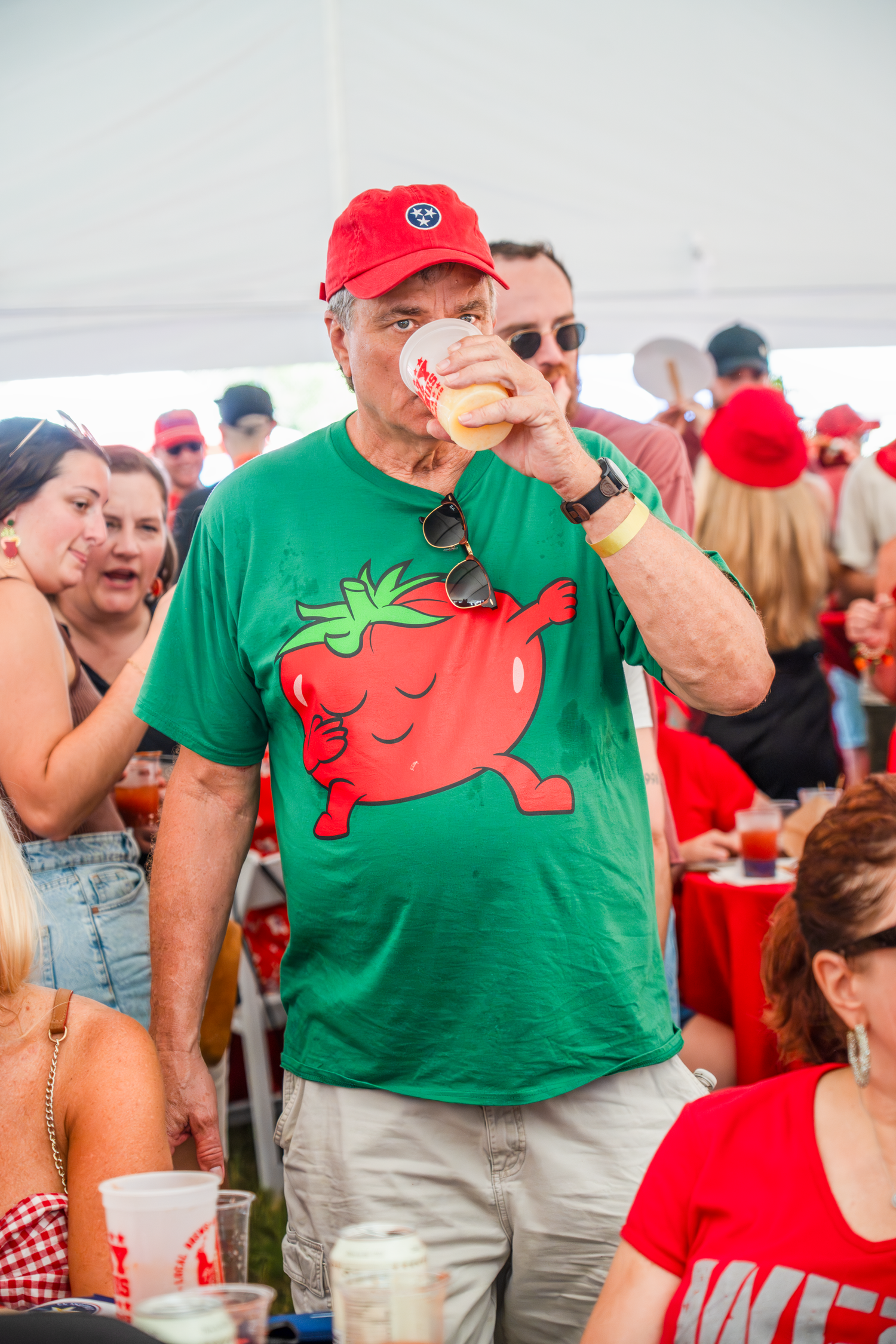People wearing green t-shirts with tomato designs at a summer festival.