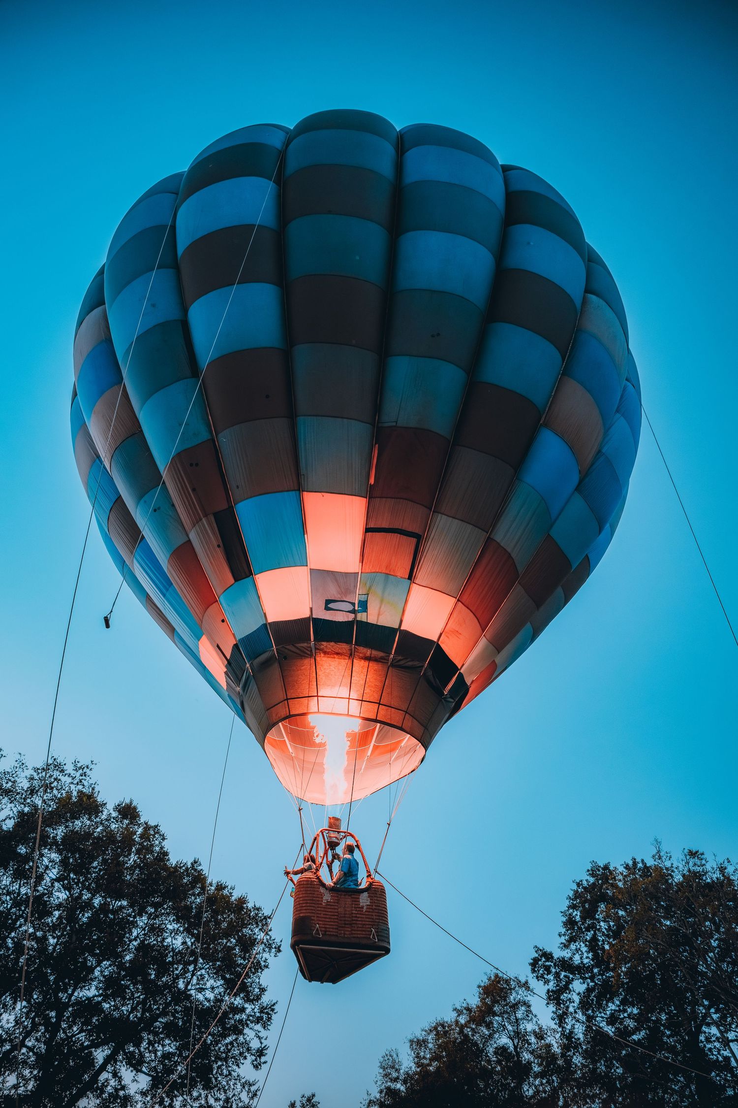 Blue and orange hot air balloon glowing against deep blue twilight sky.