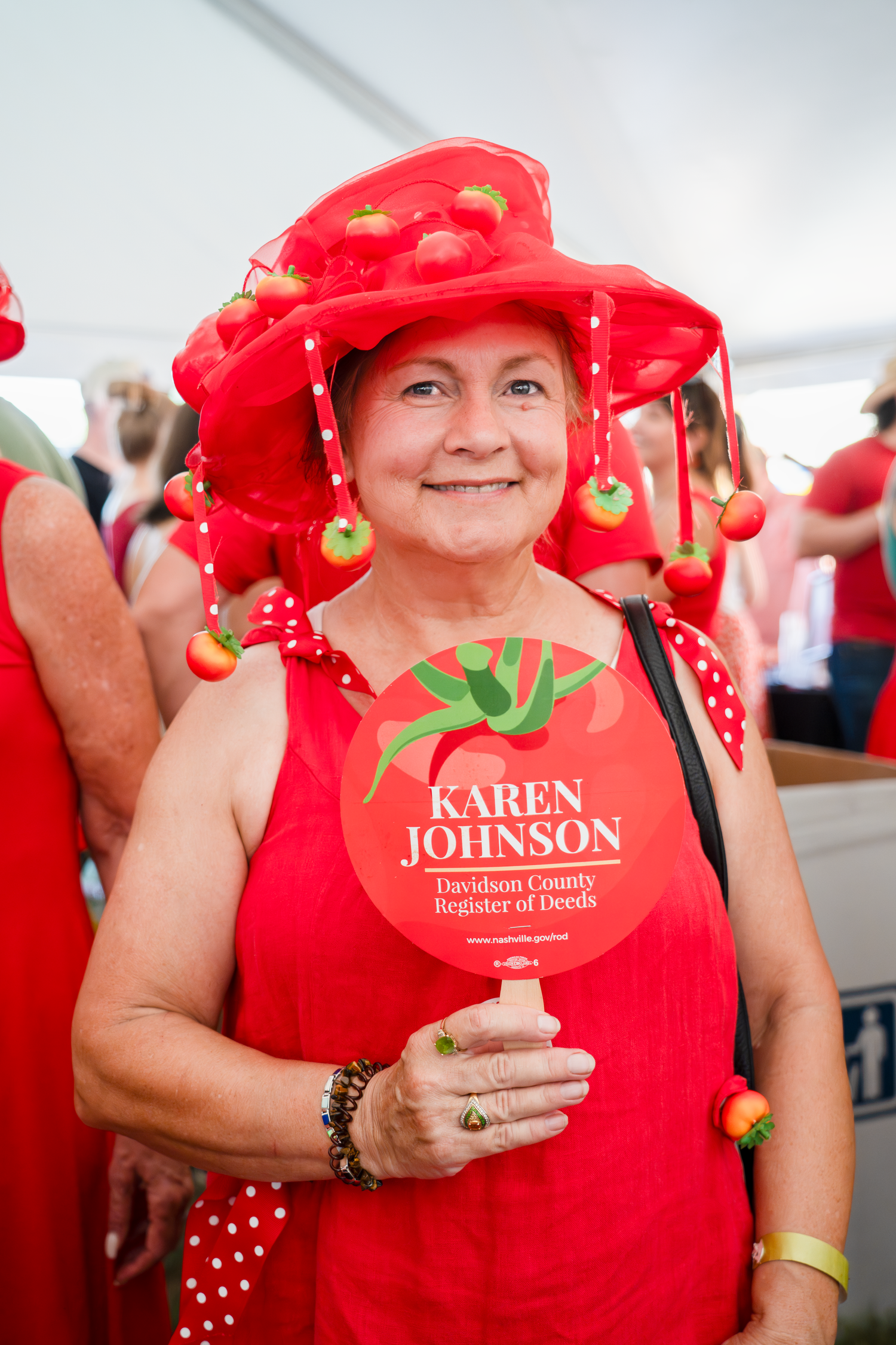 Person wearing red tomato-themed outfit with decorative accessories at a festival.
