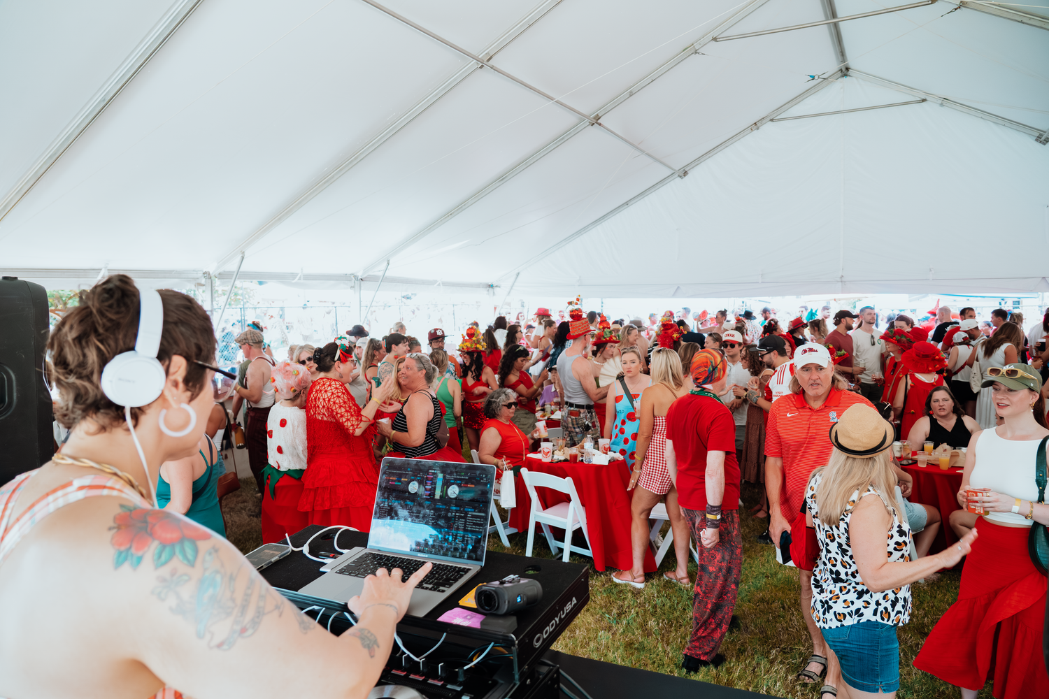 Crowded outdoor event tent with attendees dressed in red clothing.