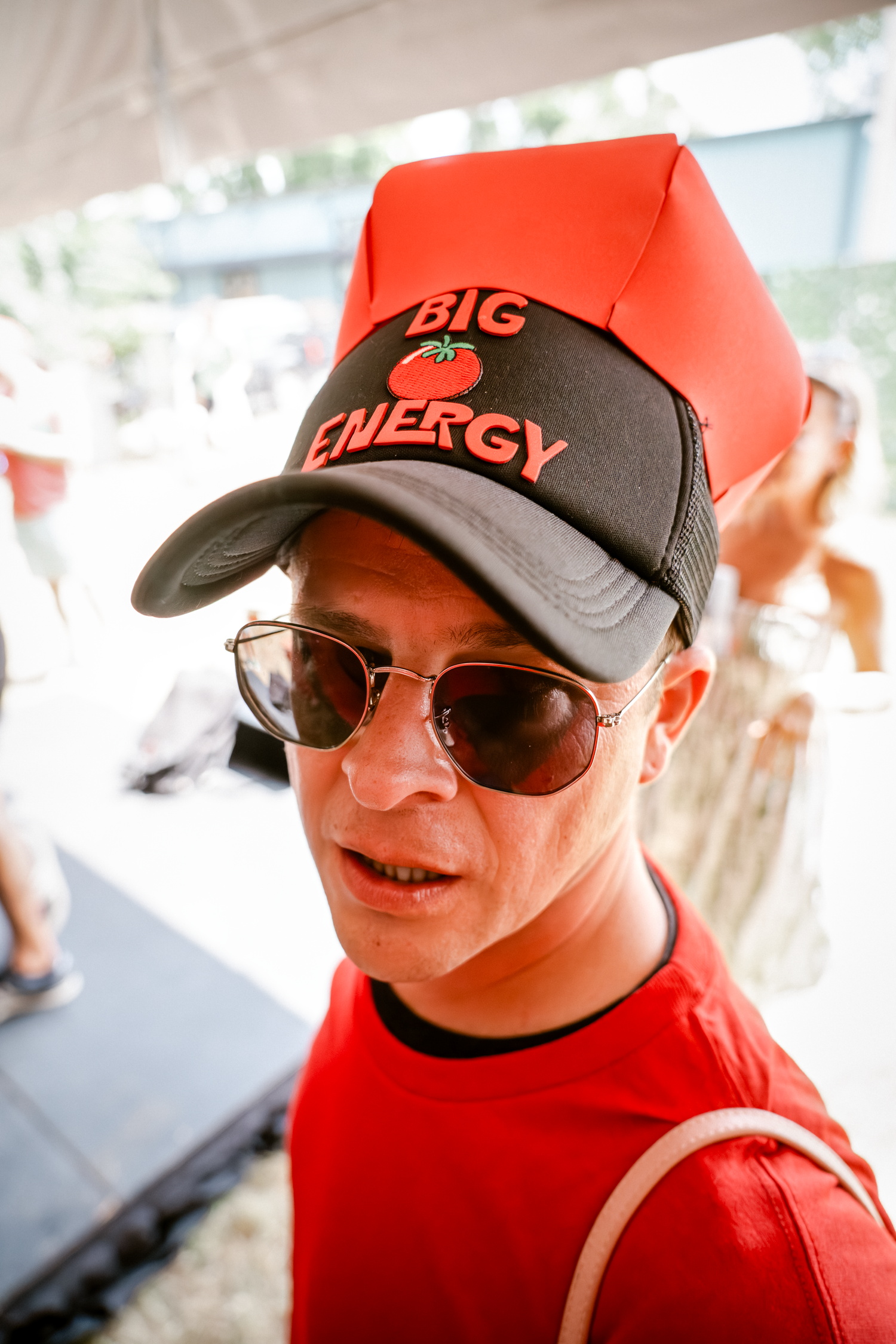People wearing red and black baseball caps with sunglasses at a summer festival.