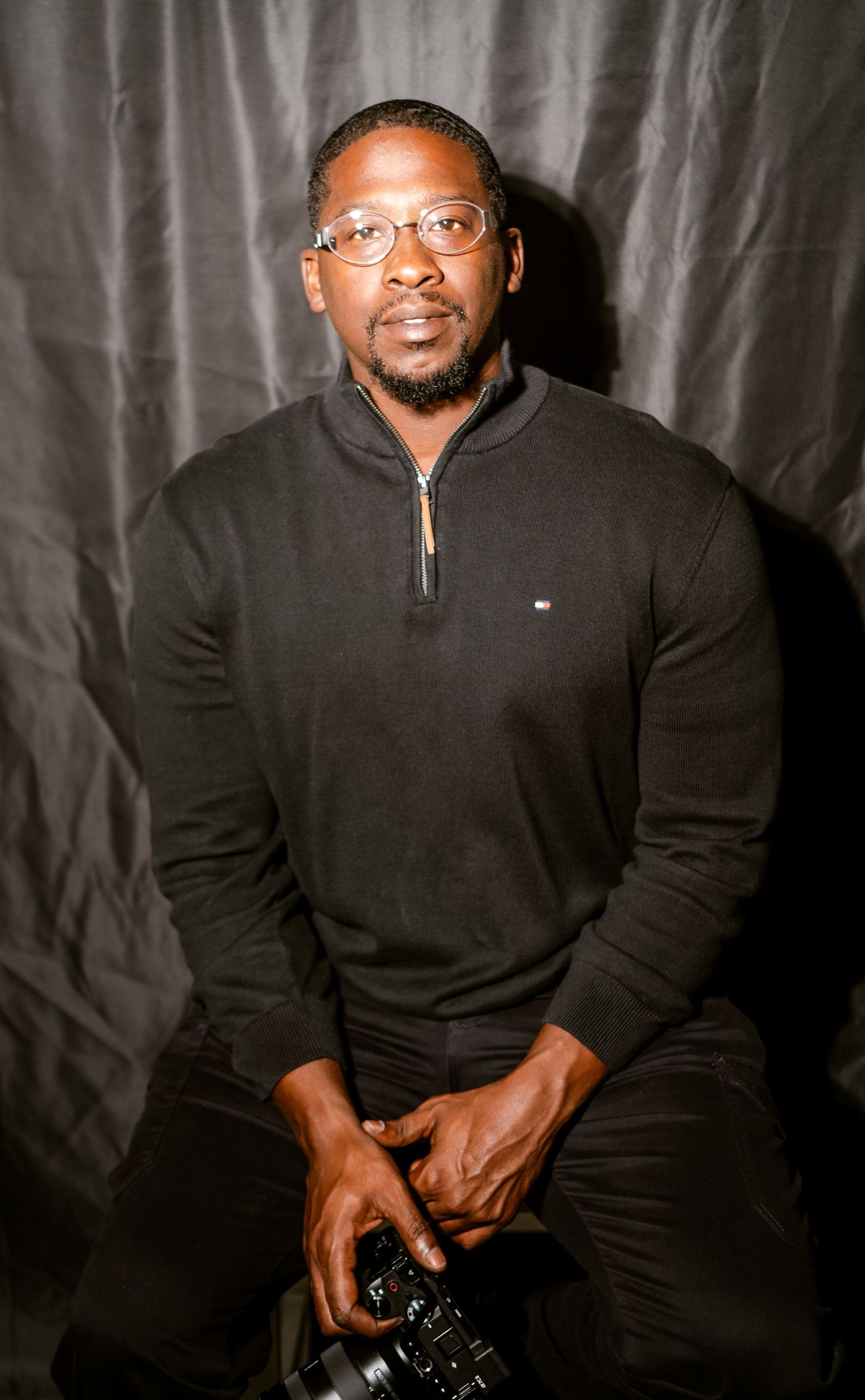 Studio portrait session against dark backdrop with camera equipment.