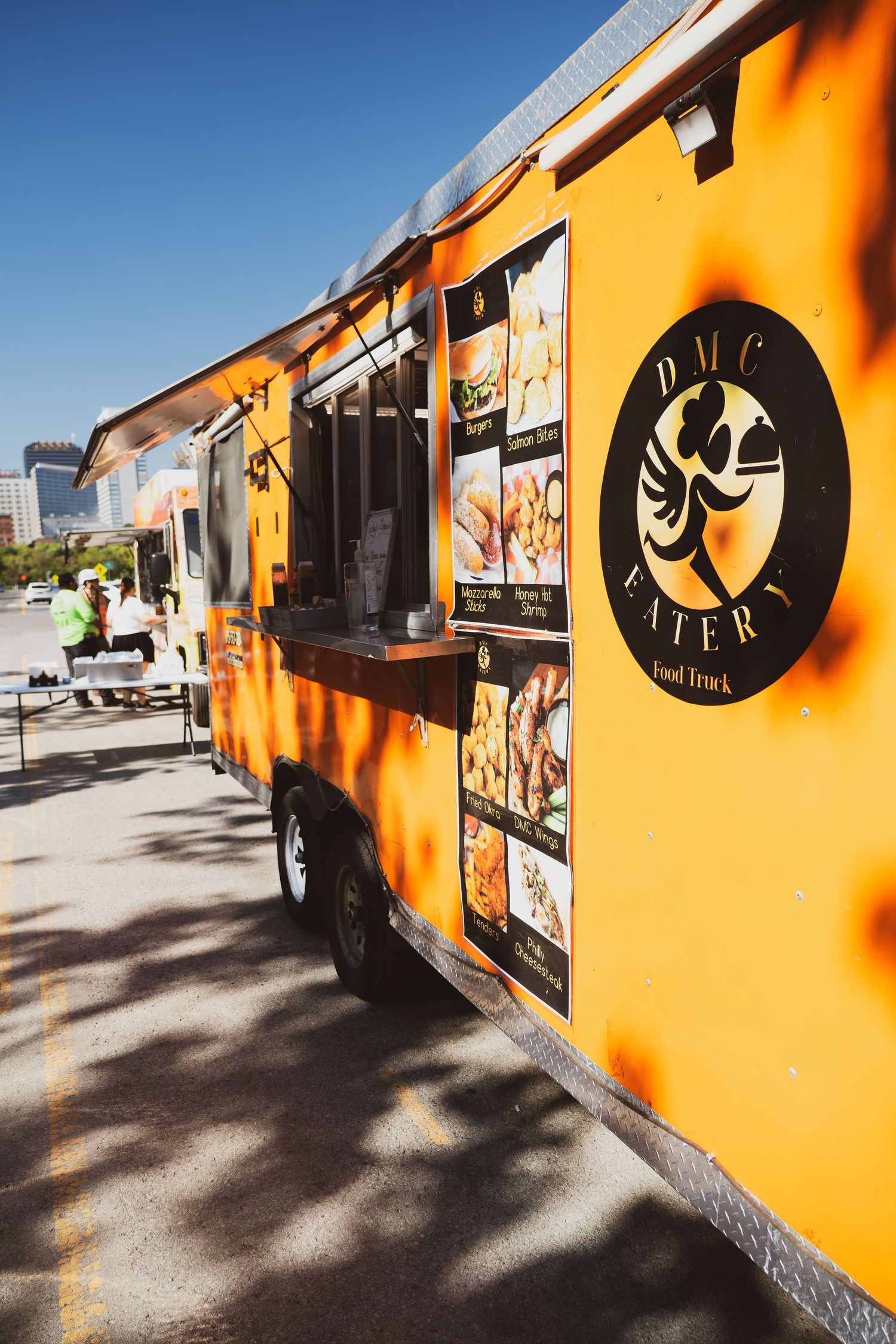 Row of bright orange food trucks with black logo designs parked at an outdoor venue.