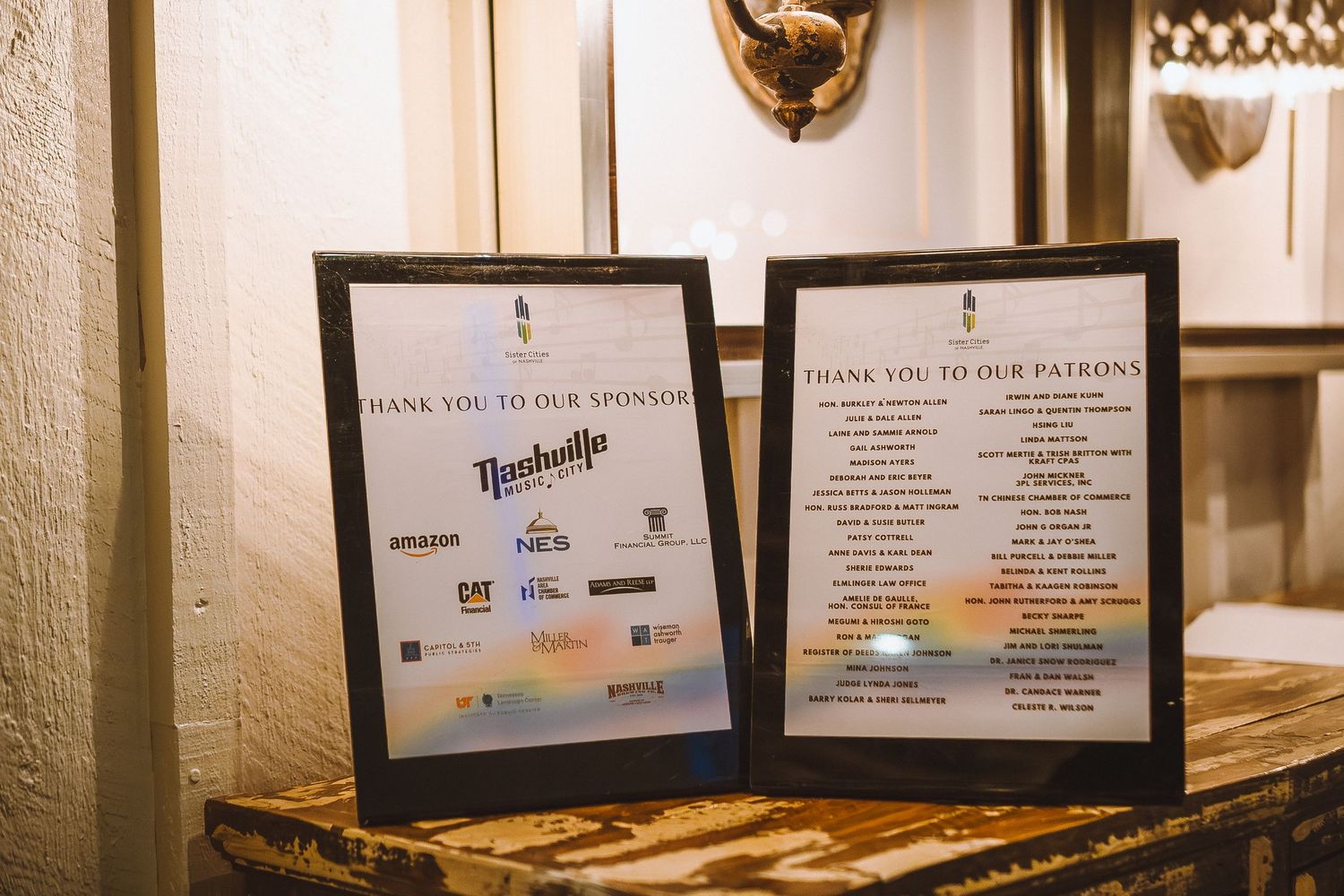 Row of framed event information and sponsor signs displayed on white wall.