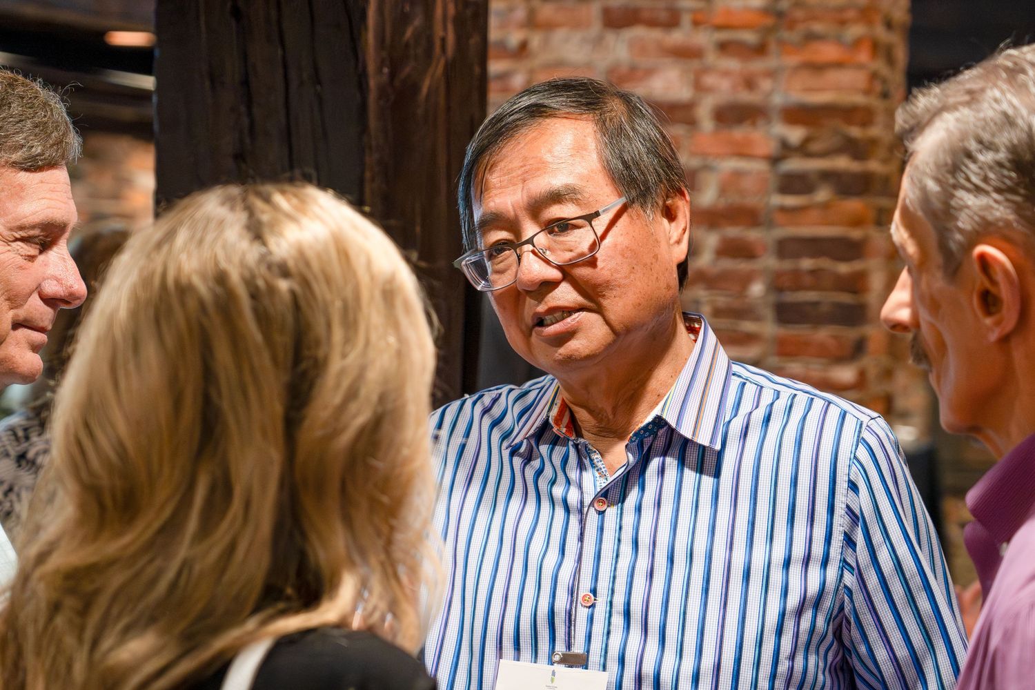 People gathered for conversation in a rustic brick-walled venue.