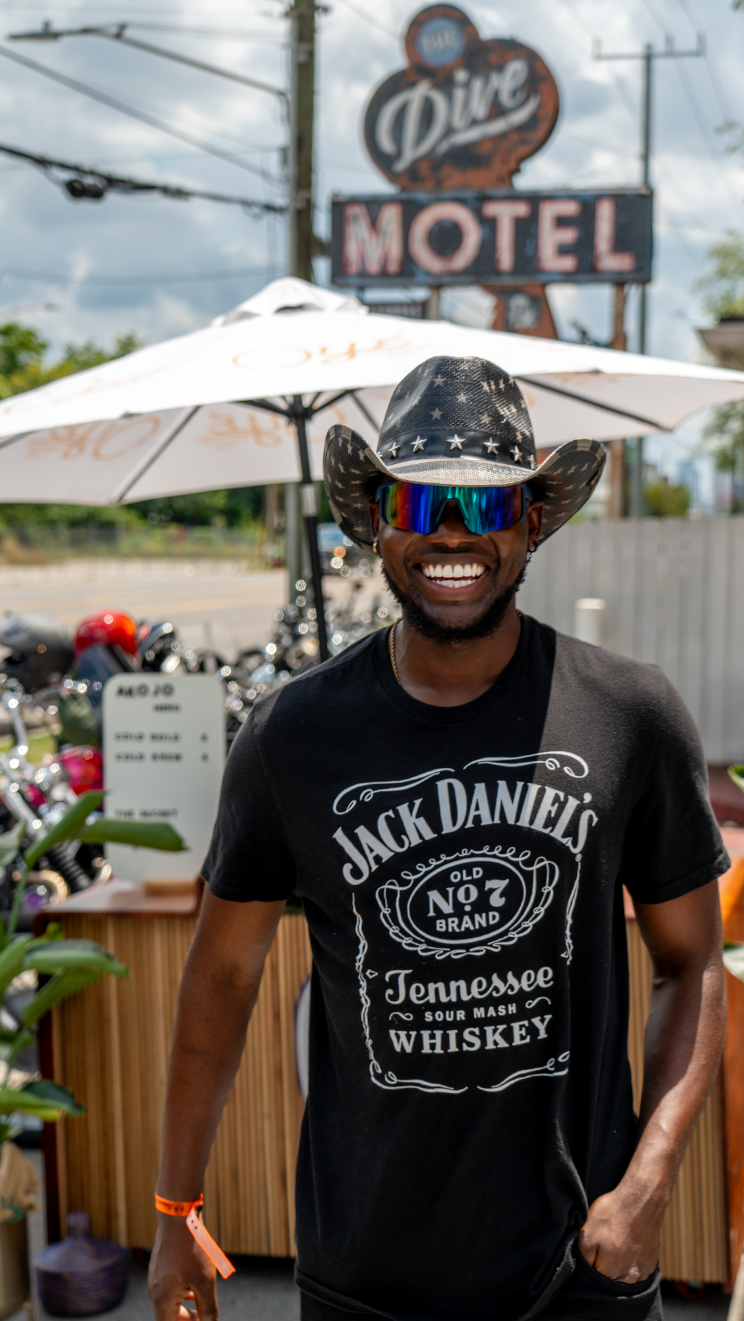 People in Jack Daniel's shirts gathered at an outdoor event with motel sign visible.