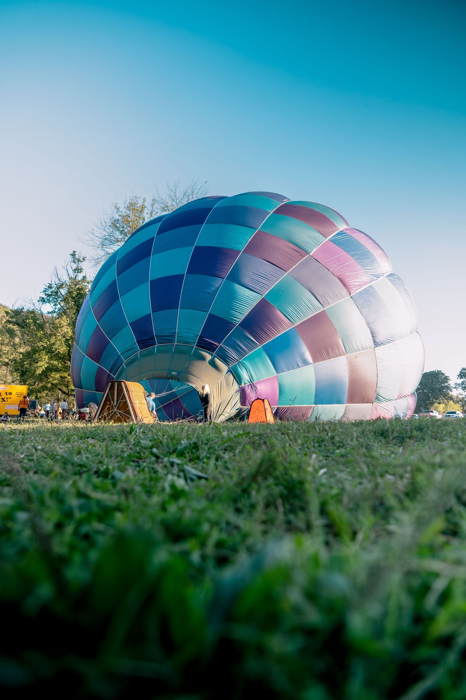 Hot air balloon preparation on ground level with vibrant blue and pink pattern.