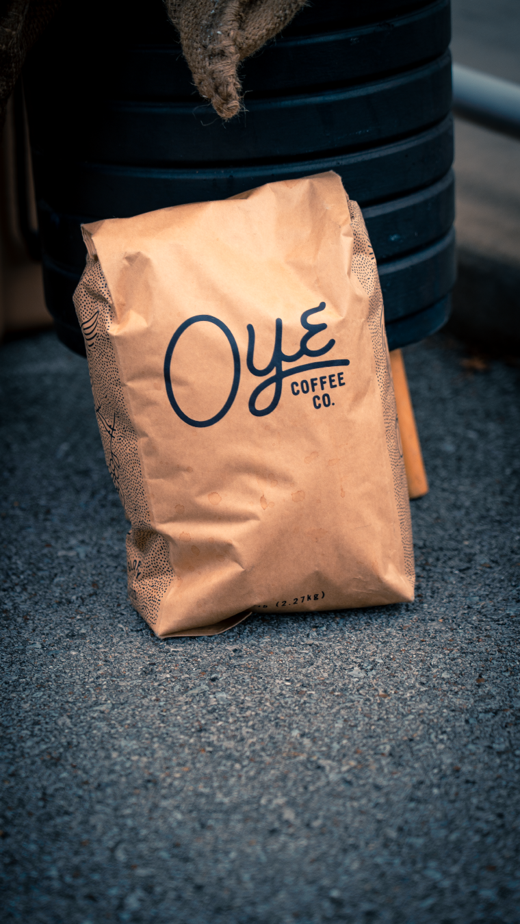 Oye Coffee Co branded paper coffee bags on dark textured surface.