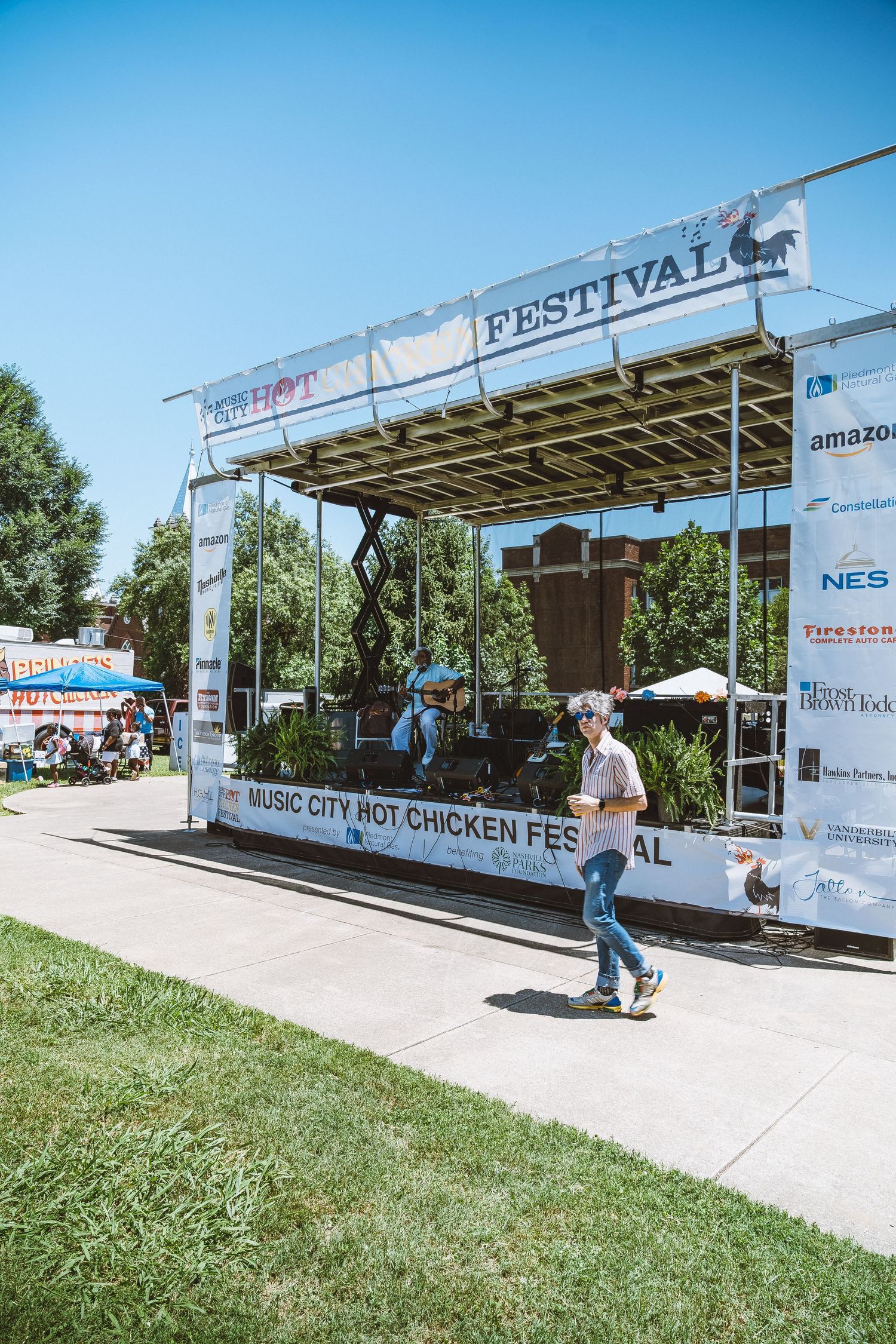 Outdoor festival area with white tents and signage set up on concrete walkway.