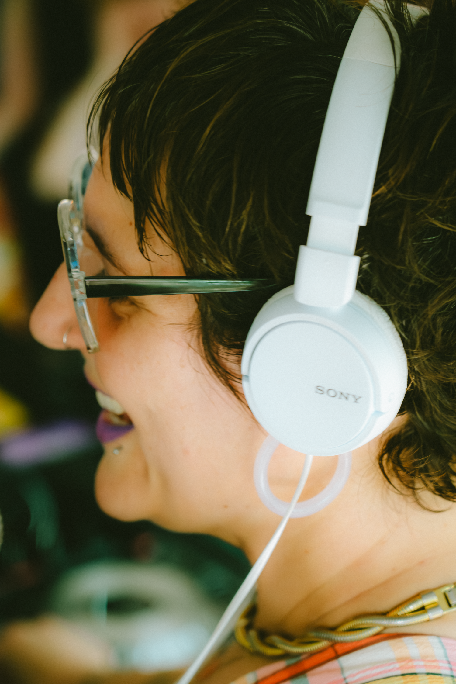 Side profile of someone wearing white Sony headphones against a blurred background.