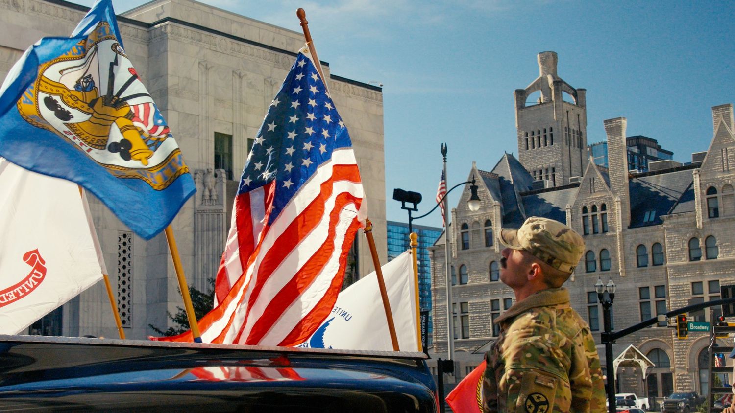 American flags and state banners wave in front of historic building architecture.