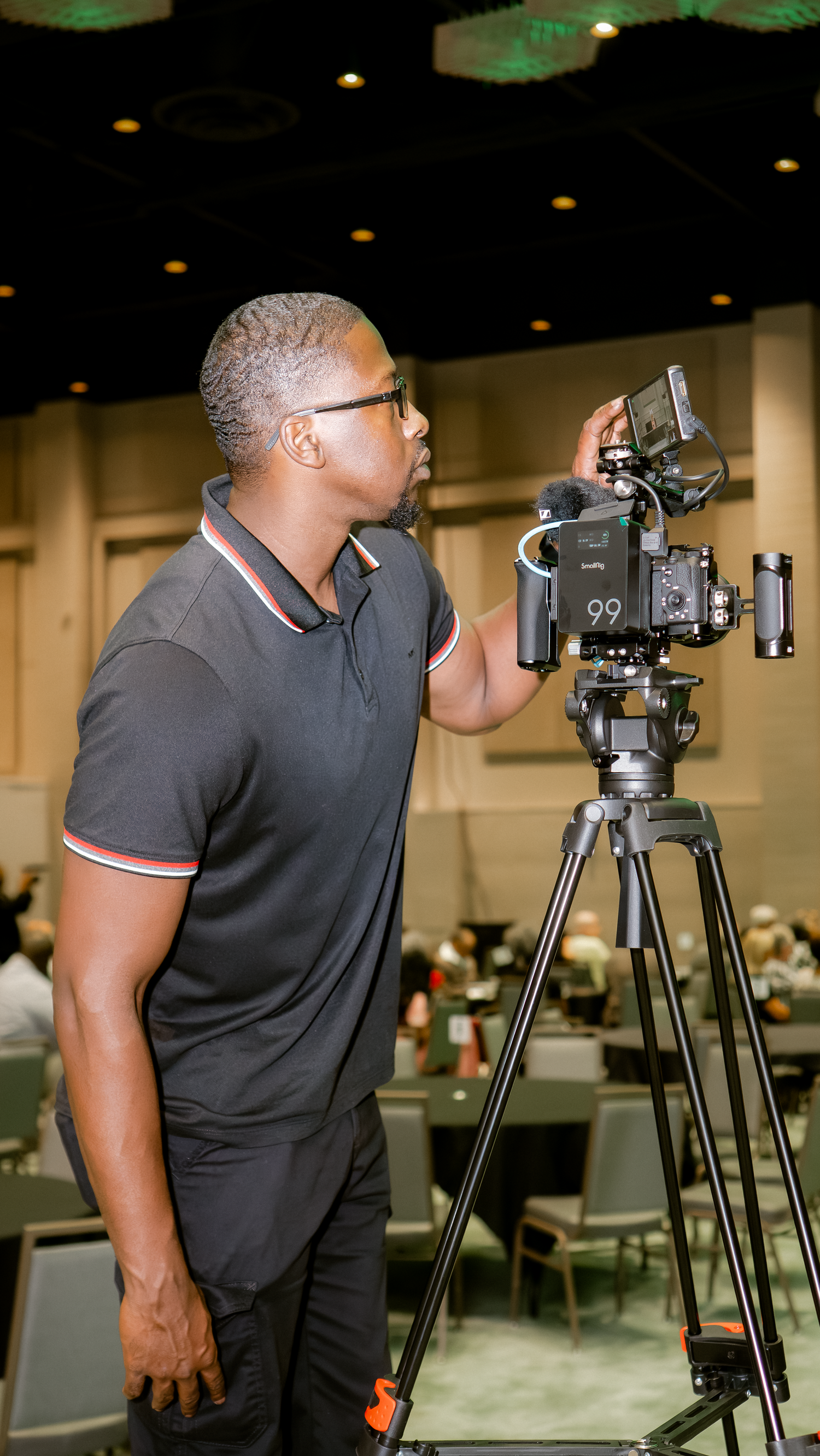 Camera operator working with professional video equipment in an indoor venue.