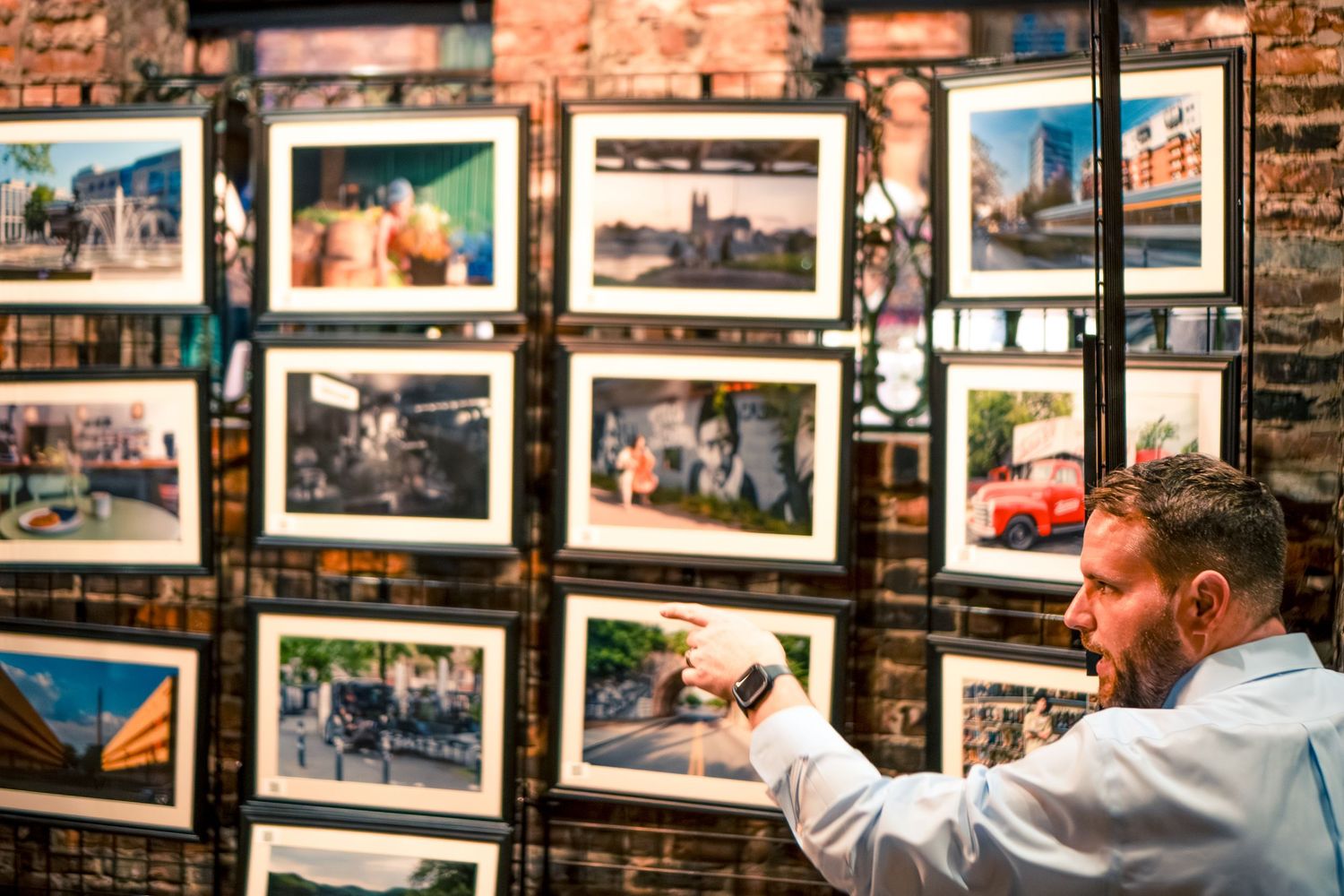 A wall display featuring multiple framed photographs in a brick-walled space.