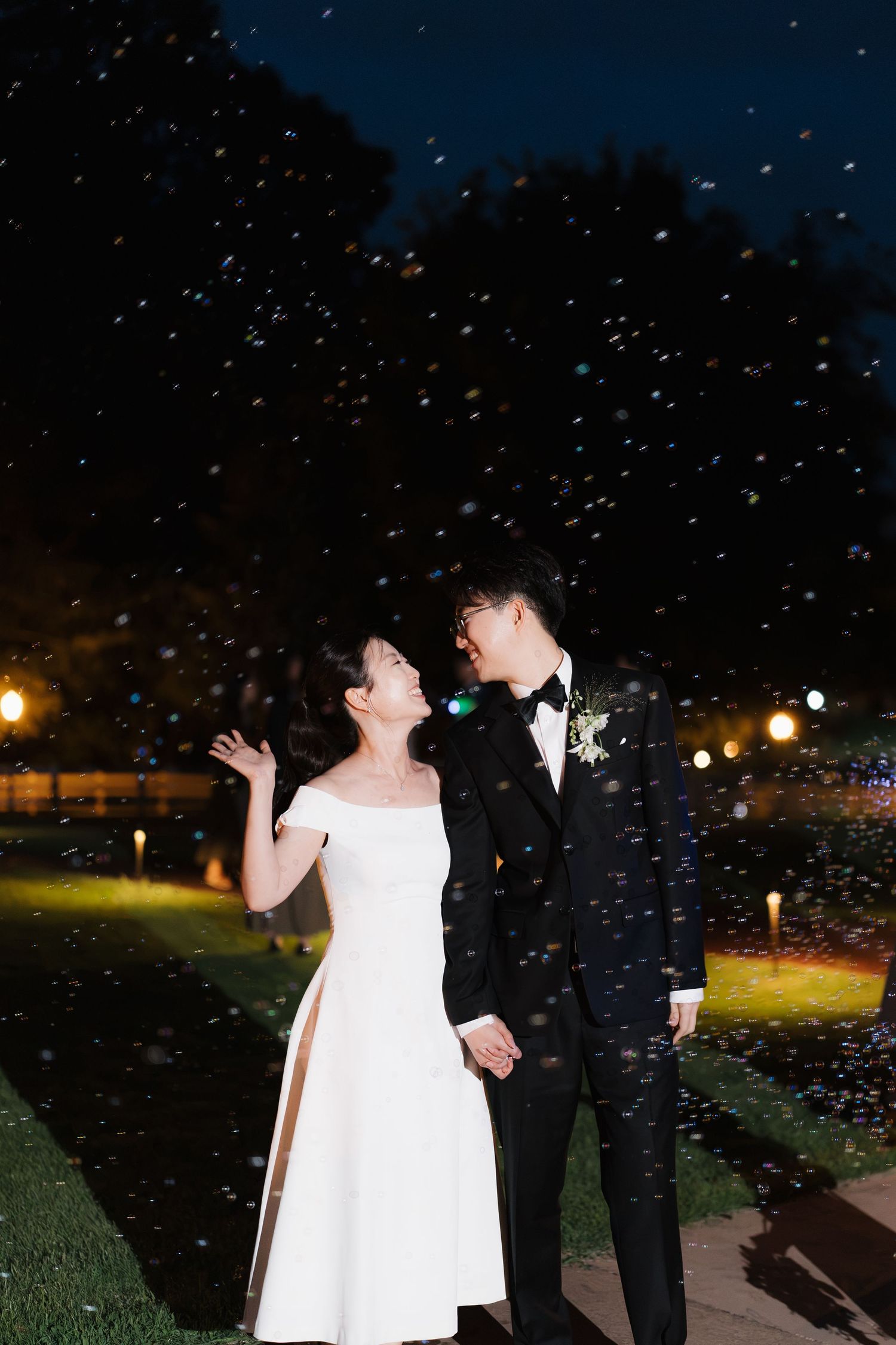 Bride and groom share a romantic moment outdoors at night surrounded by falling confetti at their wedding.