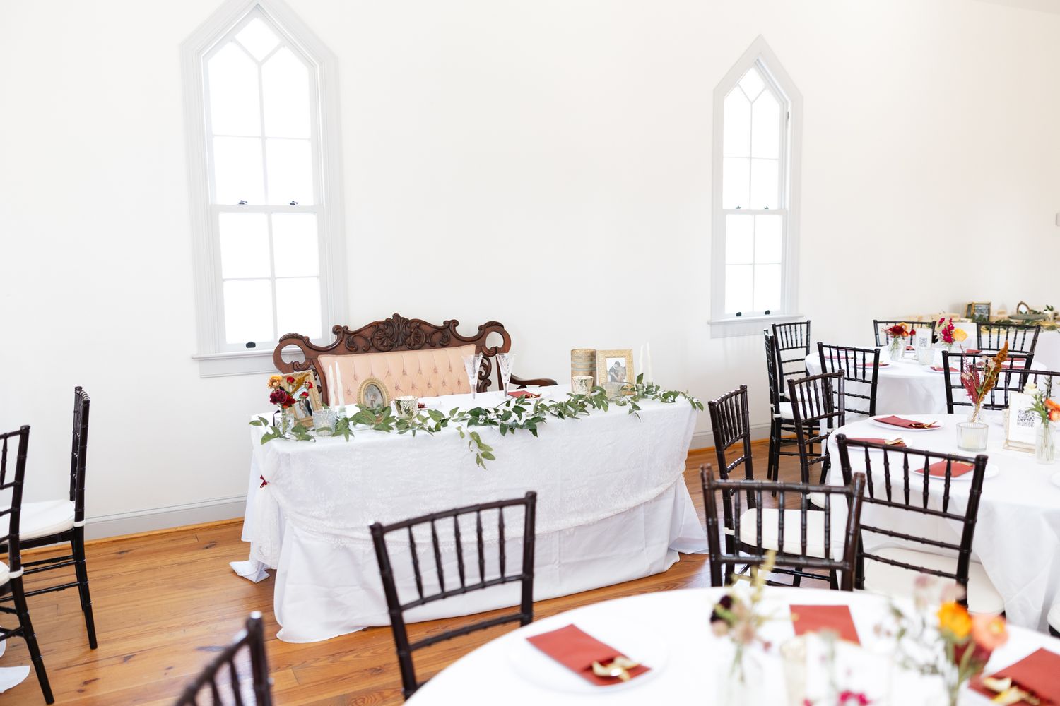 Elegant wedding reception hall with sweetheart table, greenery garland, and chiavari chairs.