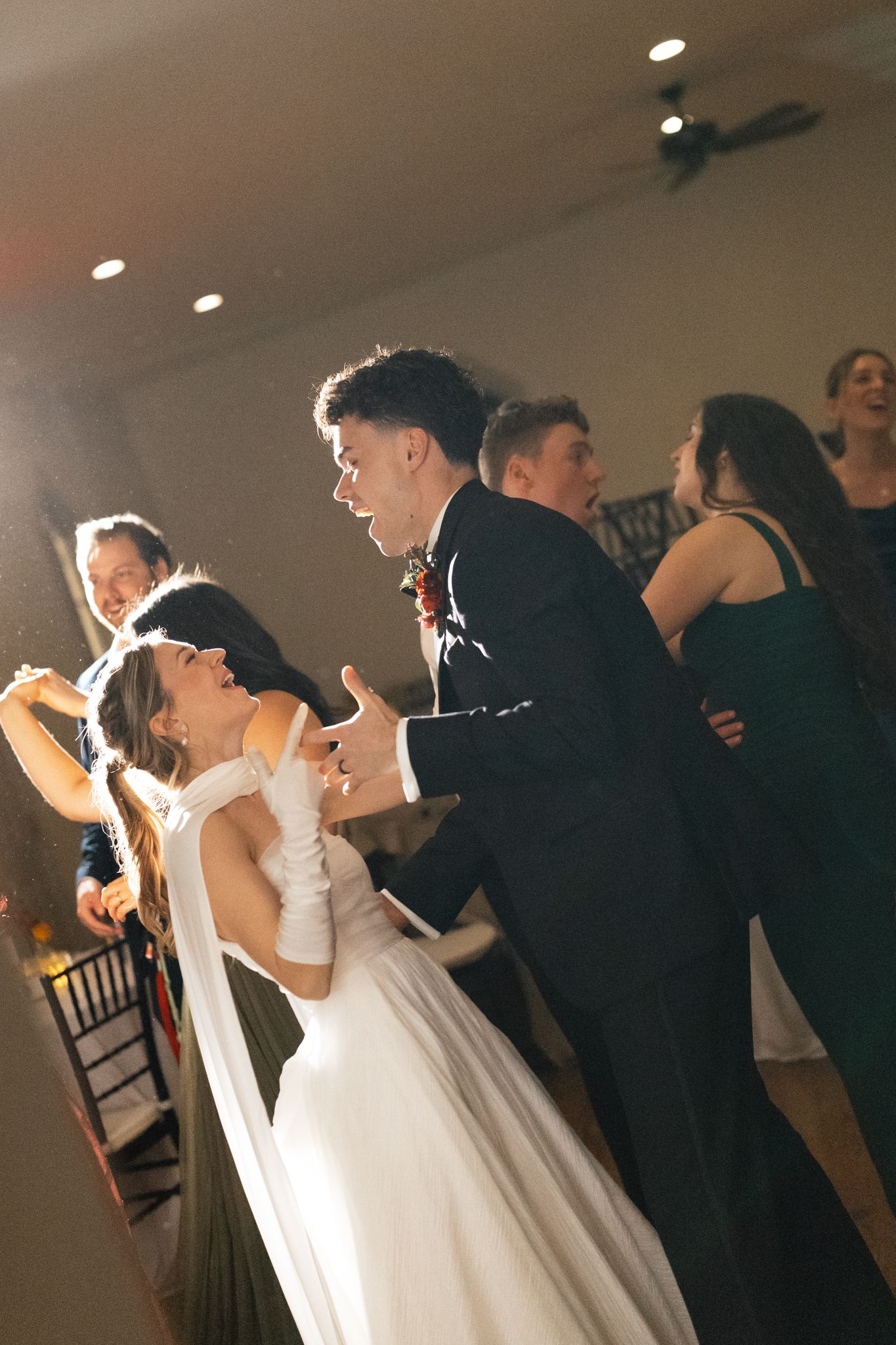 Bride and groom dancing joyfully with wedding guests on the reception dance floor.