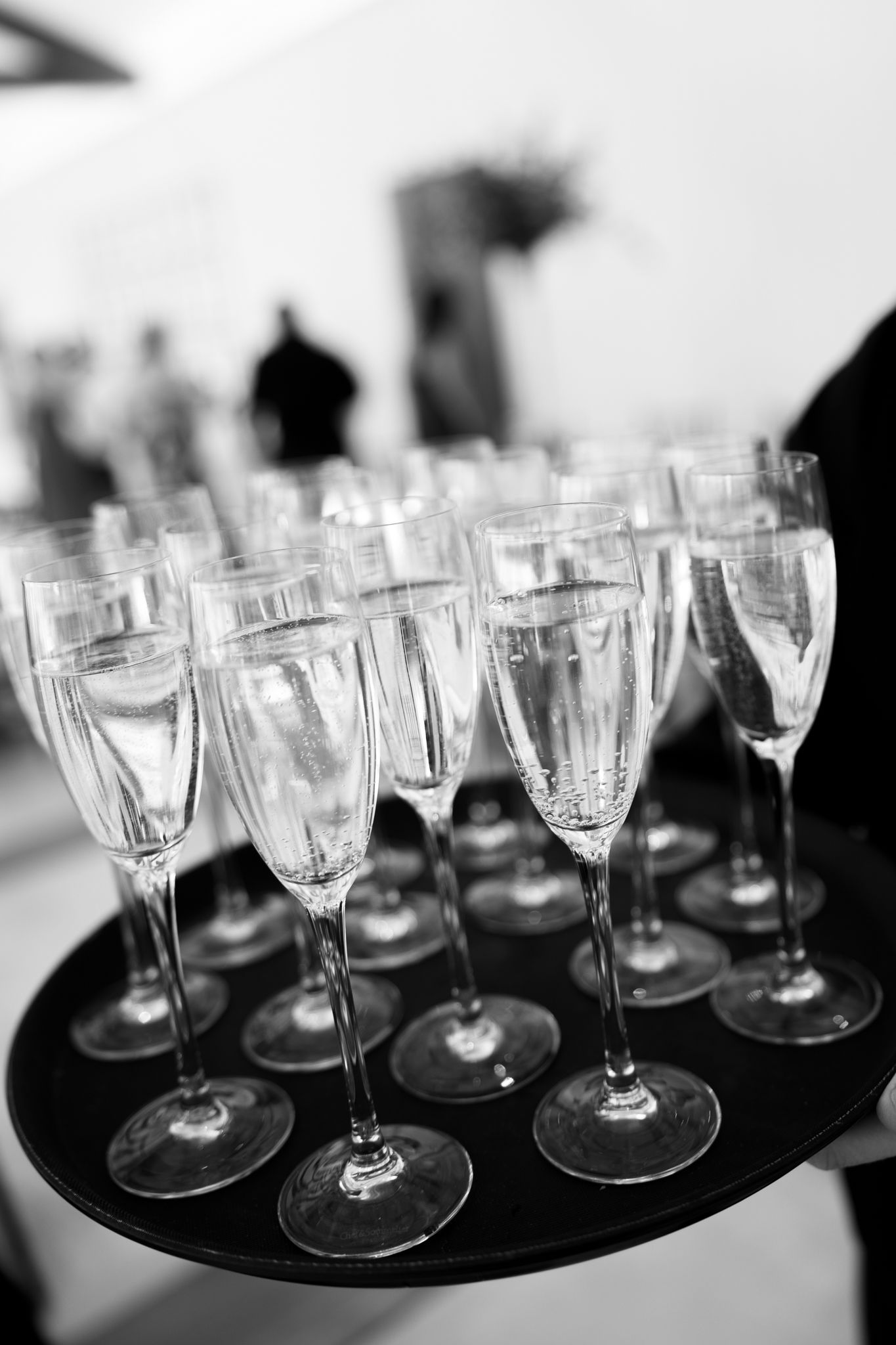Black and white photo of champagne flutes on a serving tray at a formal event.